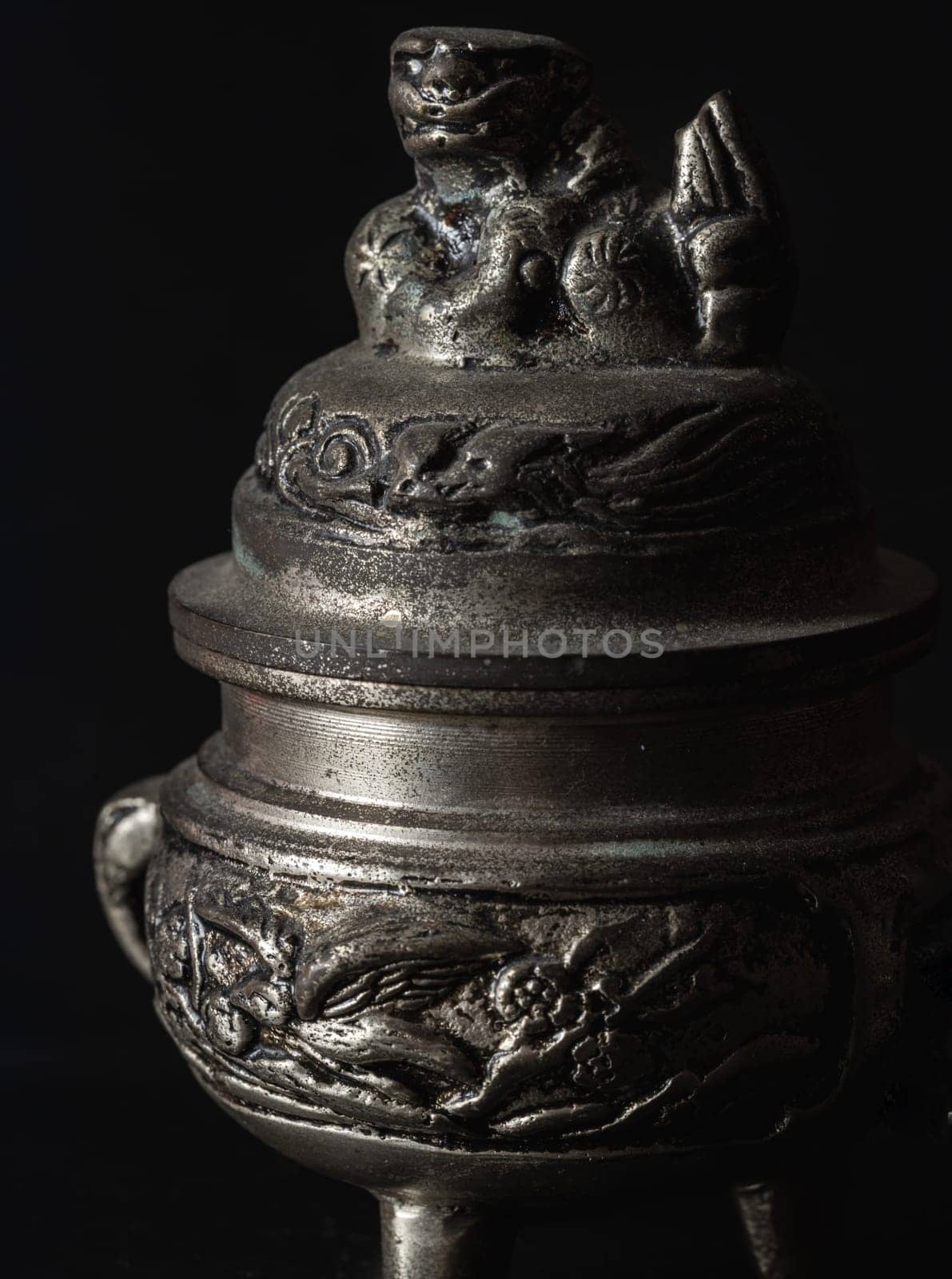 Bangkok, Thailand - 17 Sep, 2024 - Sculpture engraved decorate on small silver ancient incense burner on dark background. Antiques, Light and Shadow, Space for text, Selective focus.