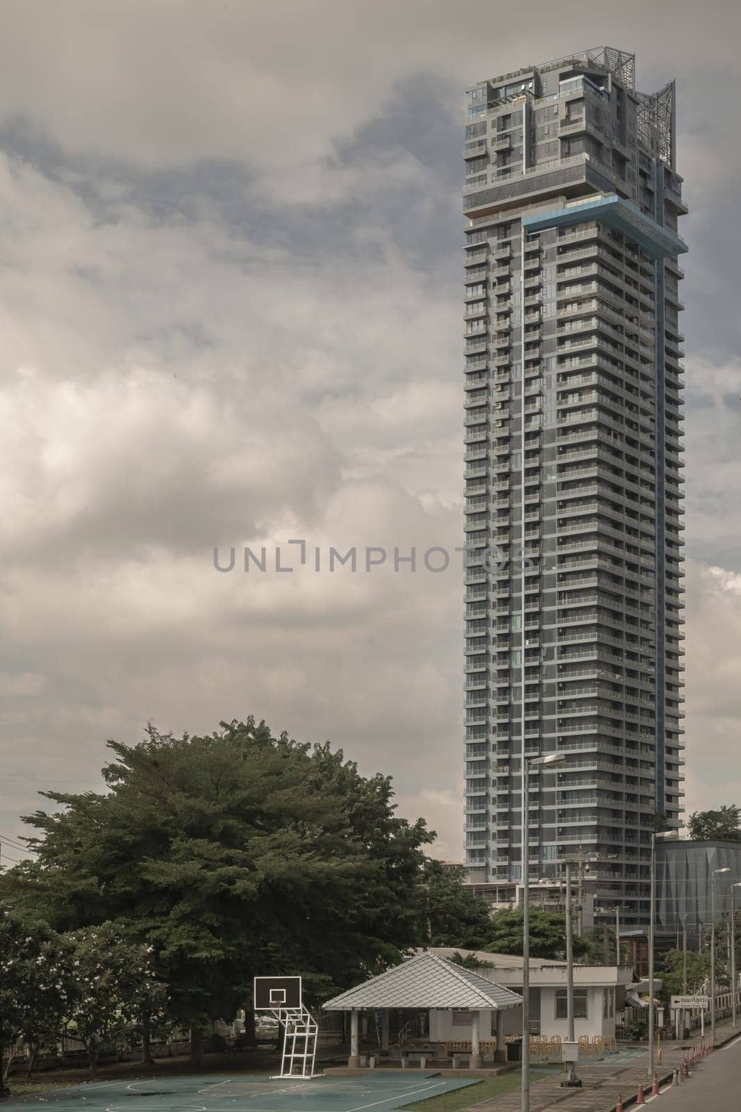 Bangkok, Thailand - 28 Sep, 2024 - Basketball backboard with the hoop metal ring in basketball court at the park with High Rise condominium building background. Space for text, Selective focus.