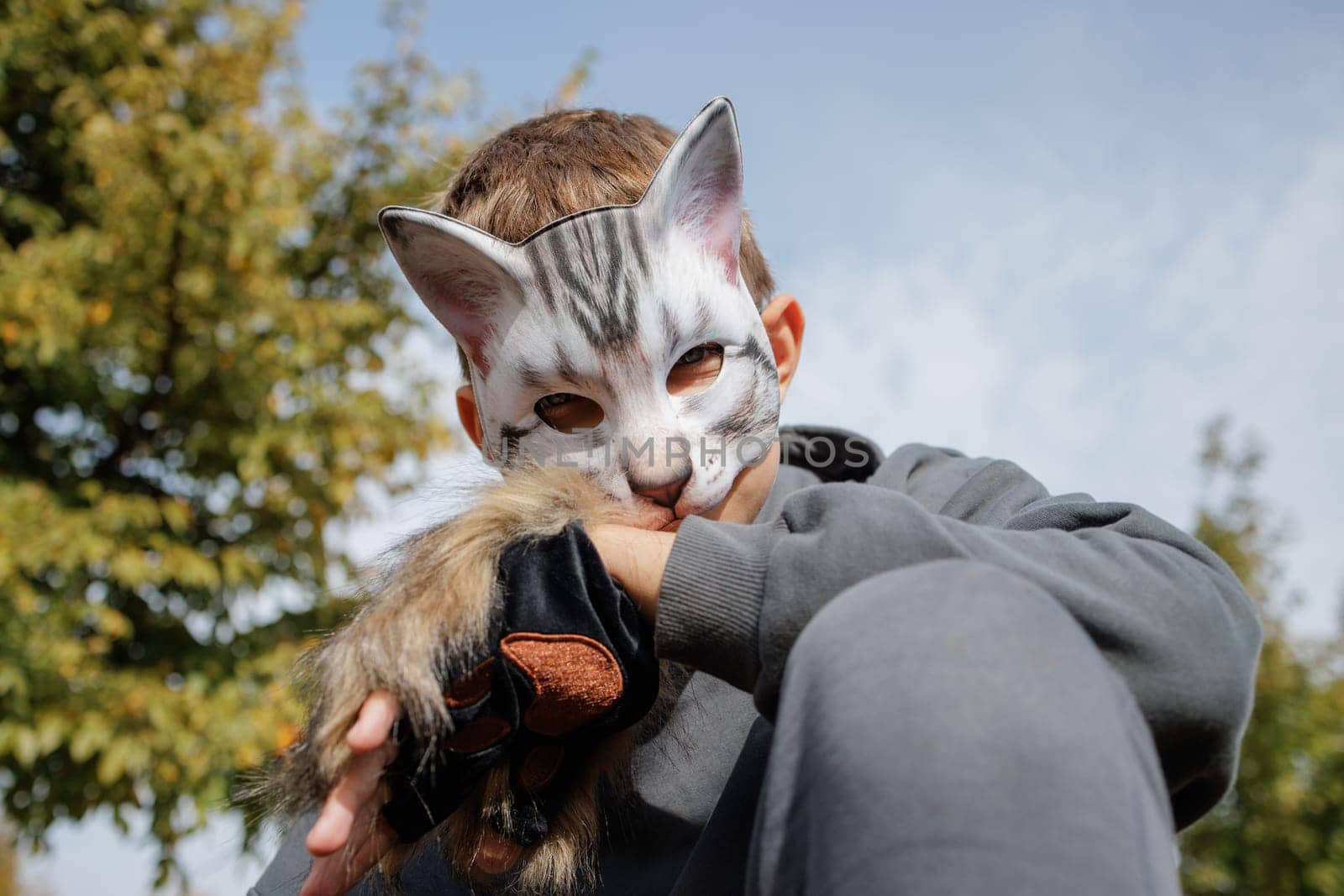 quadrobics teenager in cat mask sits on all fours in park, quadrobika subculture imitation of animal actions