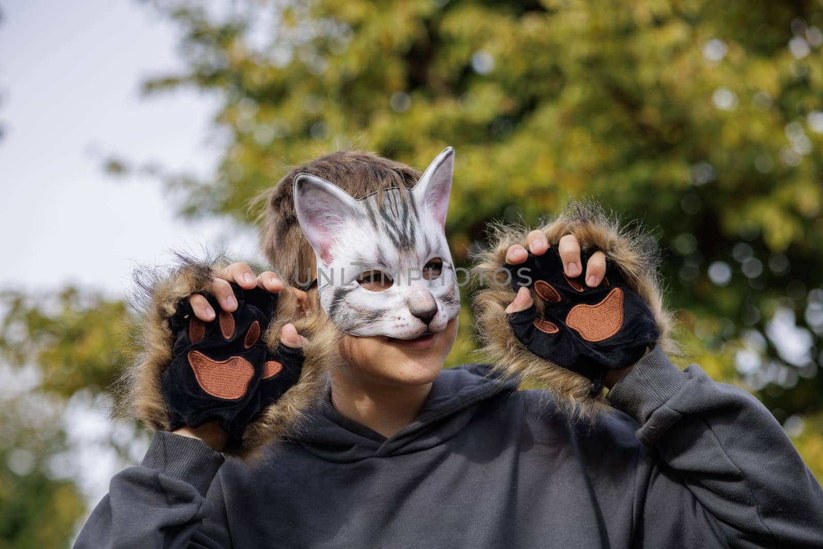 quadrobics teenager in cat mask sits on all fours in park, quadrobika subculture imitation of animal actions