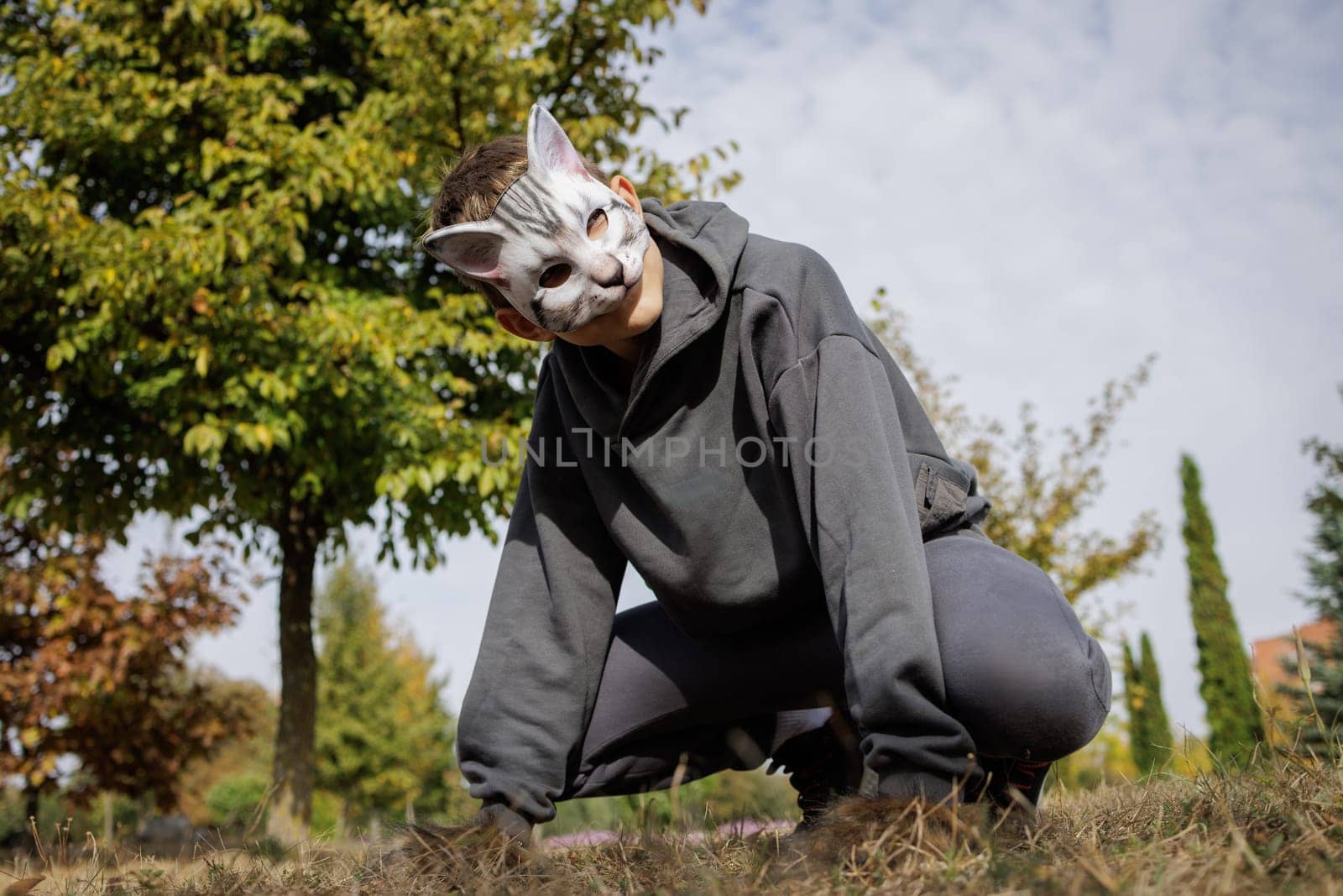 quadrobics teenager in cat mask sits on all fours in park, quadrobika subculture imitation of animal actions