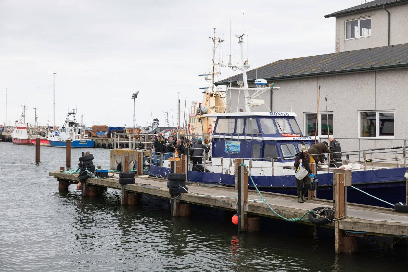 hanstholm,denmark,18-08-2024:Fishing boats are docked at a bustling harbor as fishermen prepare their gear. The scene captures the essence of maritime life and coastal work environments.