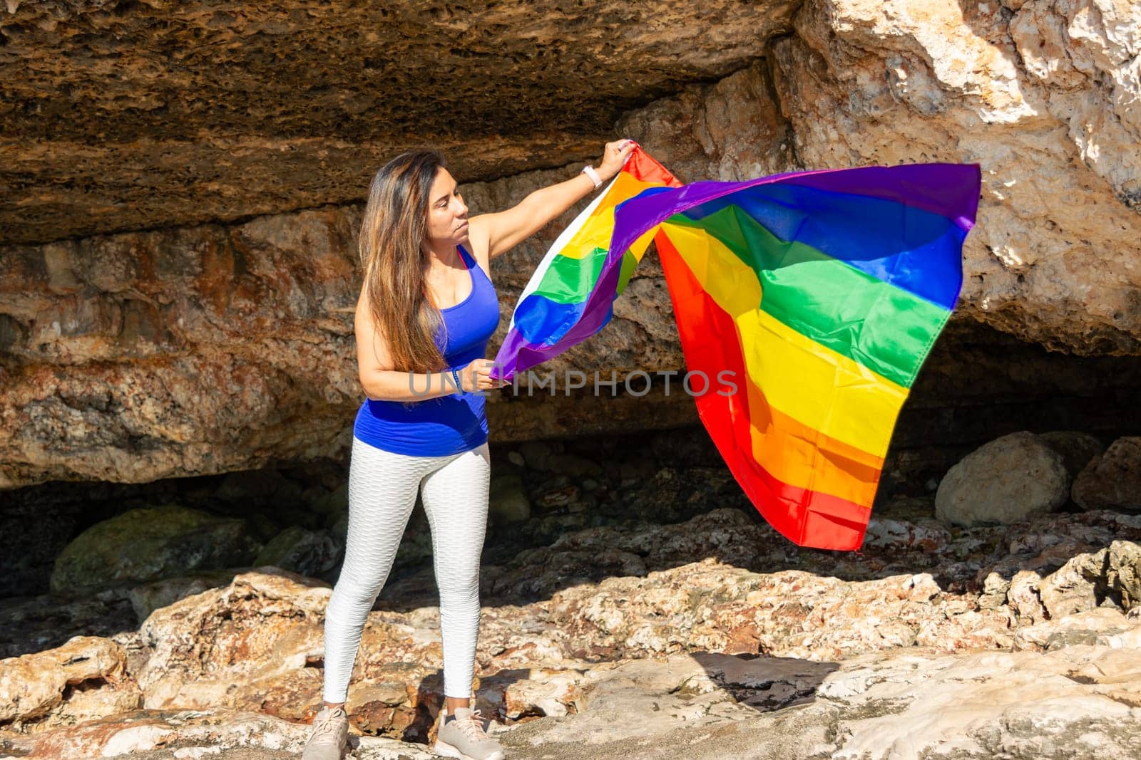woman, middle aged, outdoors waving pride flag, concept of libertat, equality.
