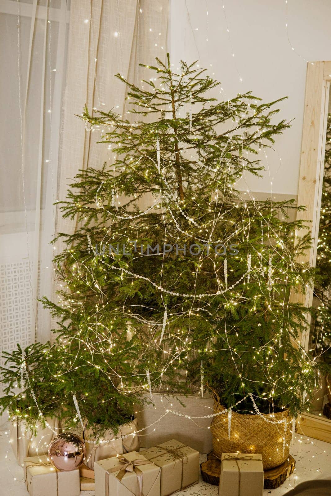 Designer Christmas tree decoration with light decorations. The concept of celebrating New Year and Christmas. Gifts in craft packaging under the Christmas tree.