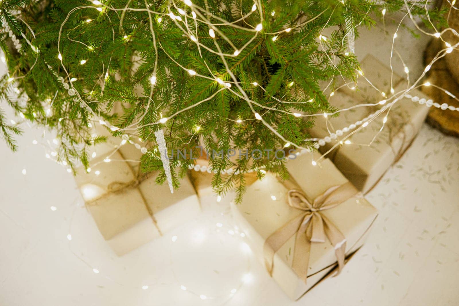 Designer Christmas tree decoration with light decorations. The concept of celebrating New Year and Christmas. Gifts in craft packaging under the Christmas tree.
