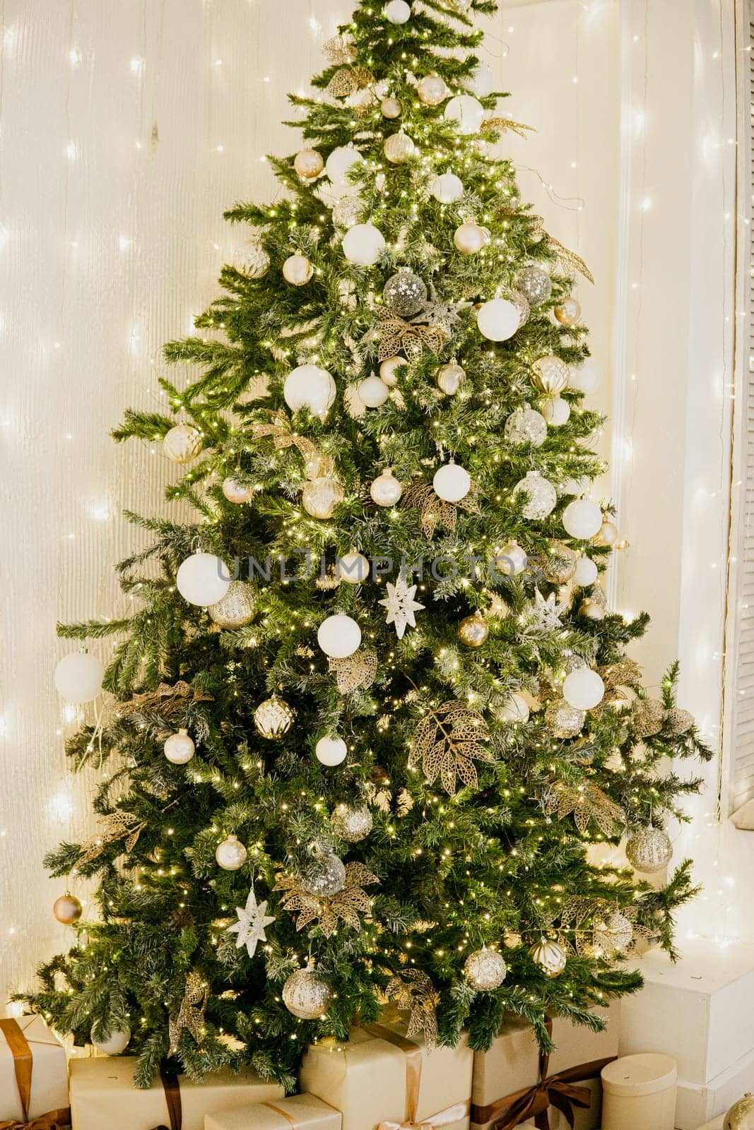 A large Christmas tree in the living room, decorated with garlands and light balloons. Bright Christmas interior