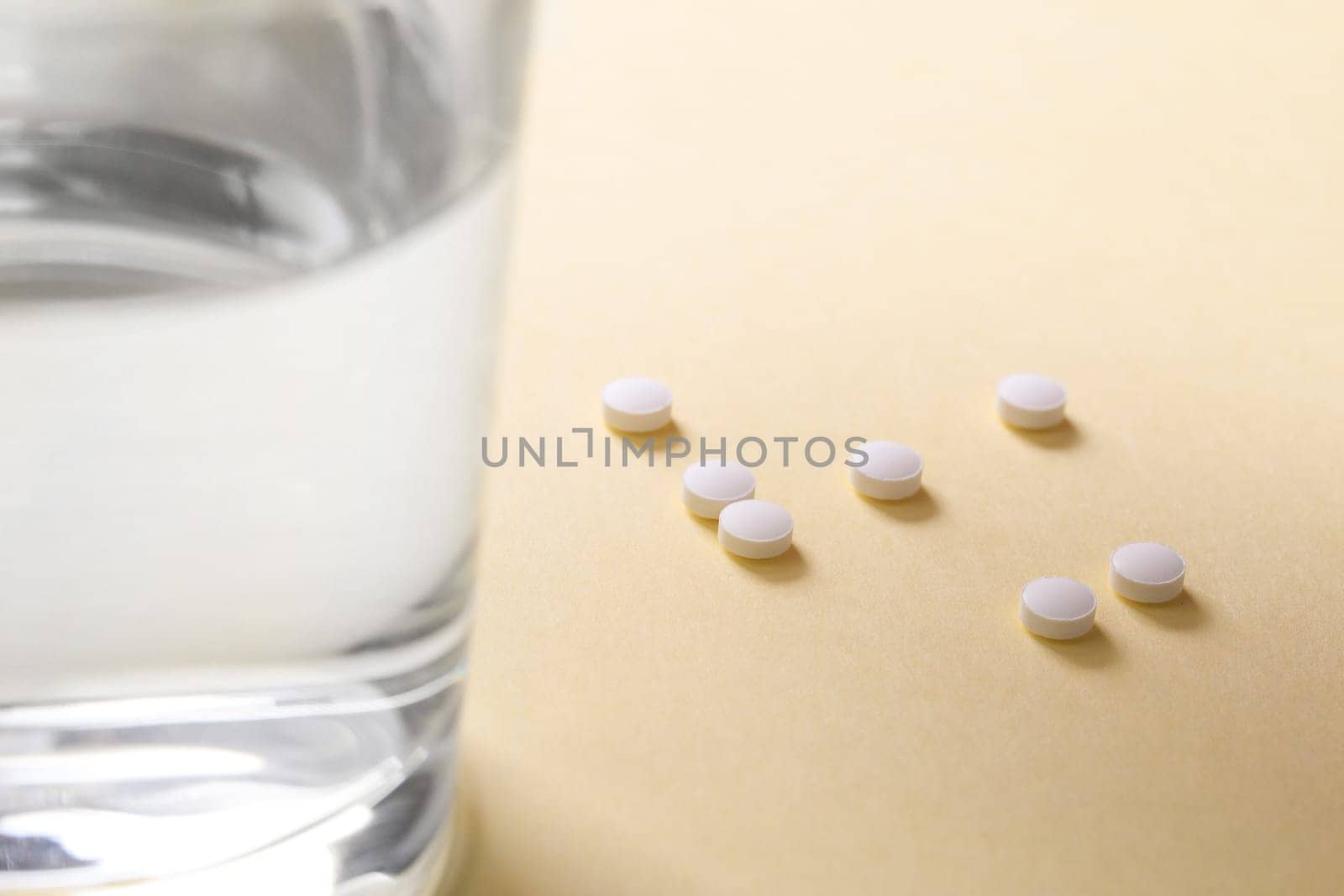 Pills on the table next to a glass of water, copy space.