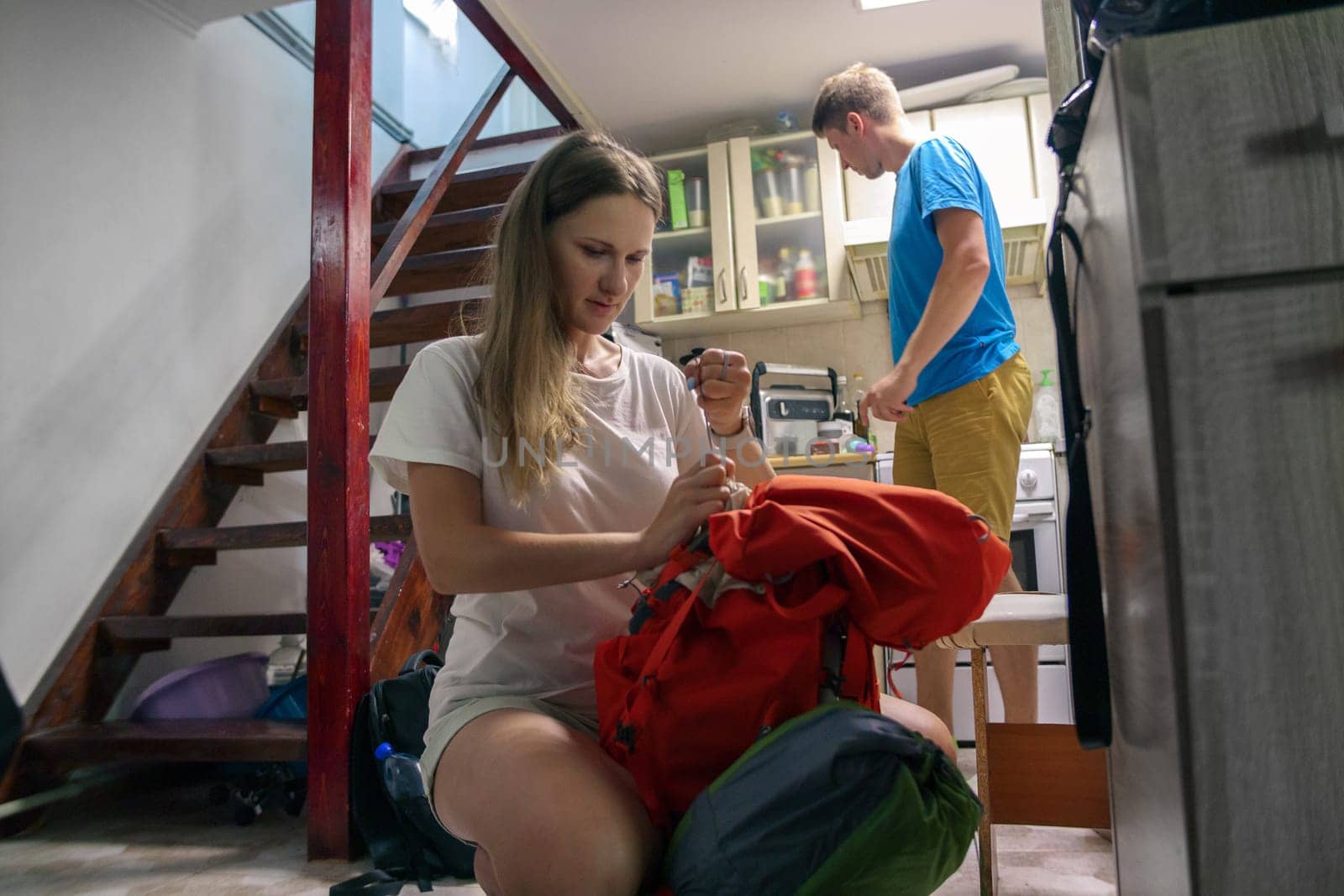 Two enthusiastic travelers are organizing their gear for an exciting outdoor journey in a cozy indoor setting