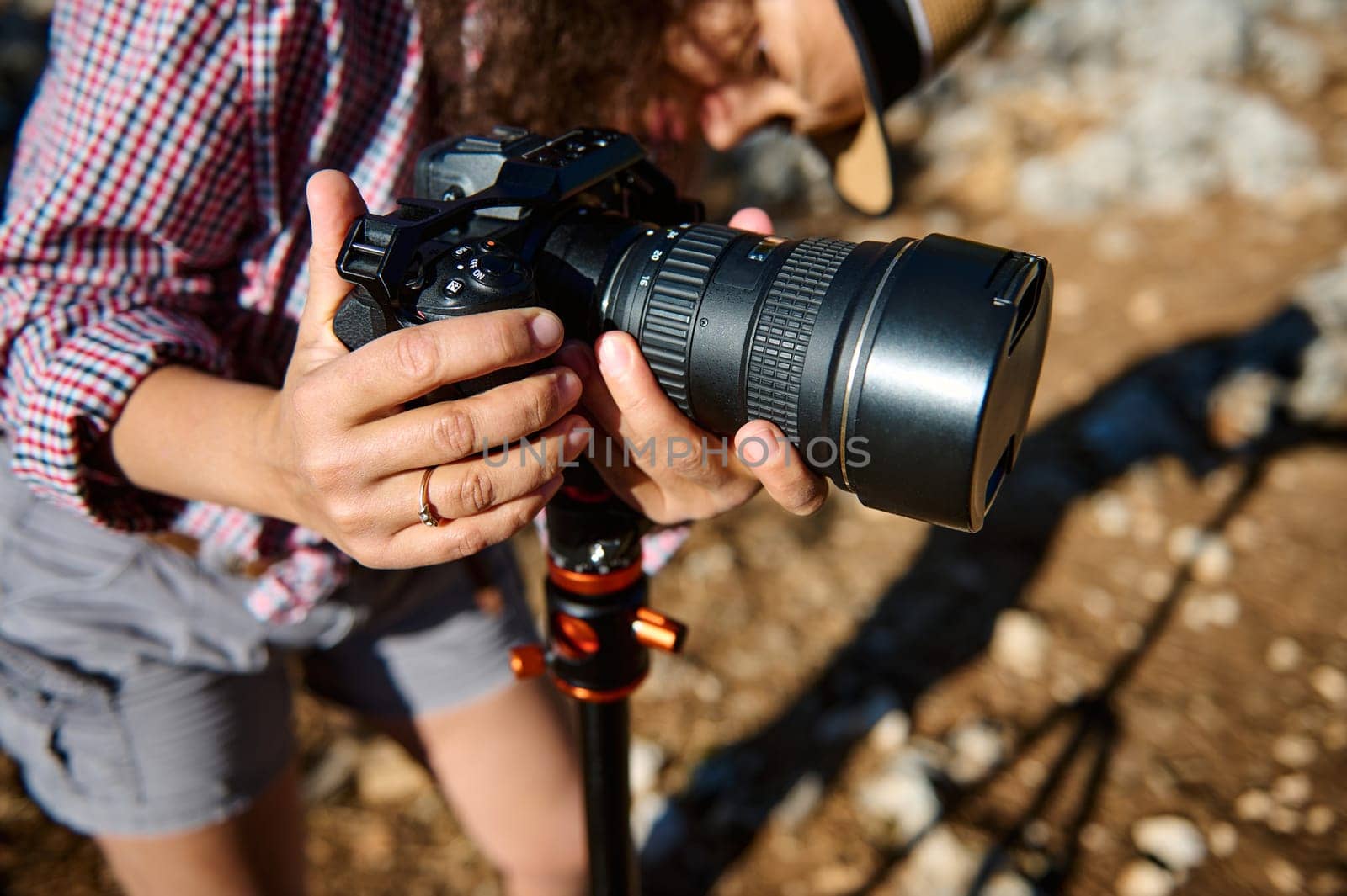 Close-up view of a photographer adjusting a camera on a tripod outdoors. Capturing a perfect shot in natural light, showcasing the art and skill of photography.