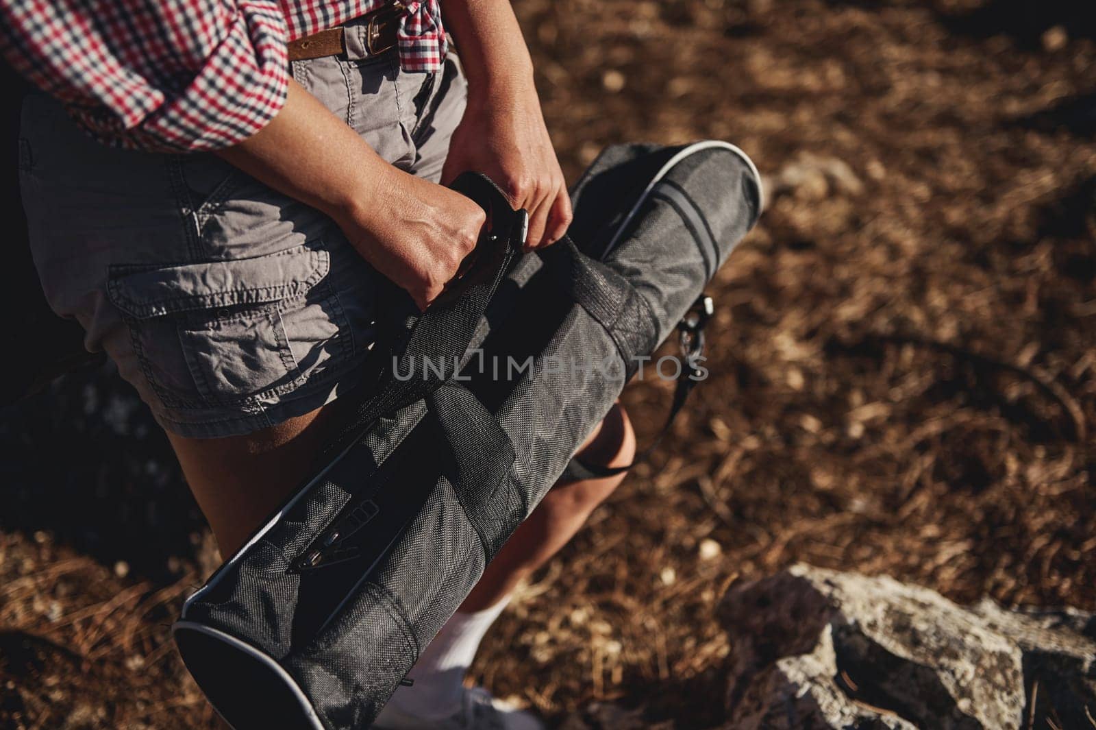 A close-up image of a person in casual outdoor attire holding a portable folding stool while outdoors, emphasizing readiness and practicality.
