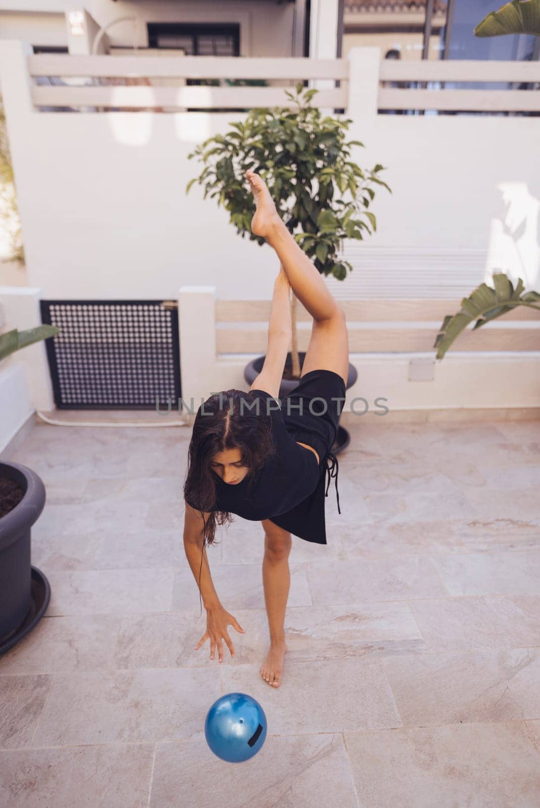 A young child demonstrating remarkable flexibility and balance while engaging joyfully with a ball in the outdoors