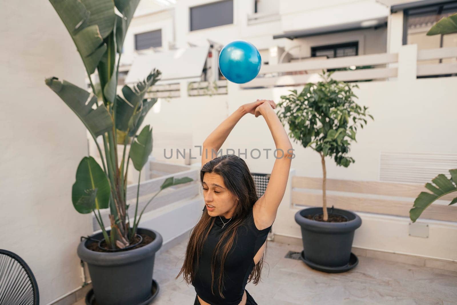 A woman is energetically performing a dynamic fitness routine with an exercise ball in a stylish, bright setting