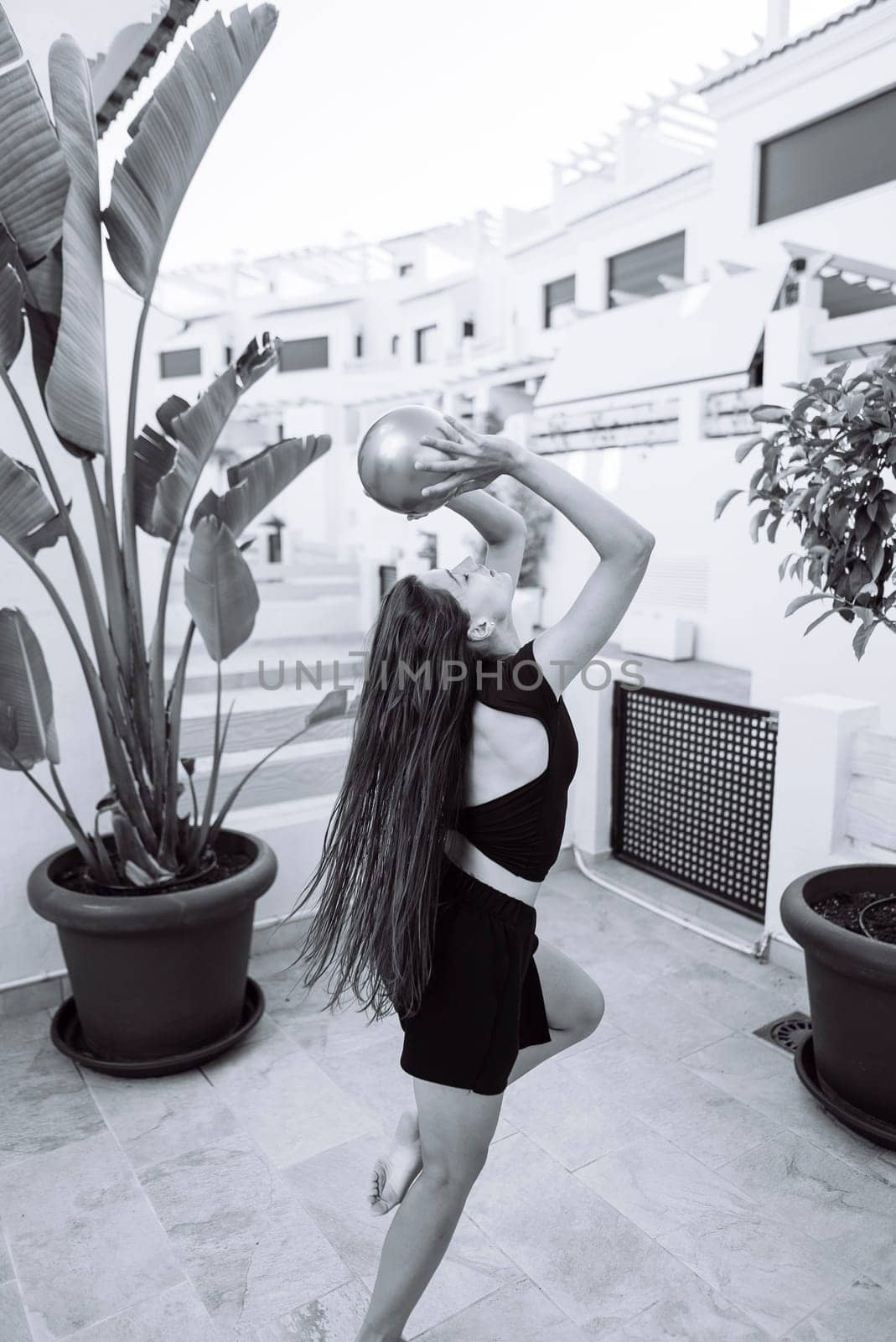 A talented dancer strikes an elegant pose with a vibrant basketball against a stunning chic outdoor setting