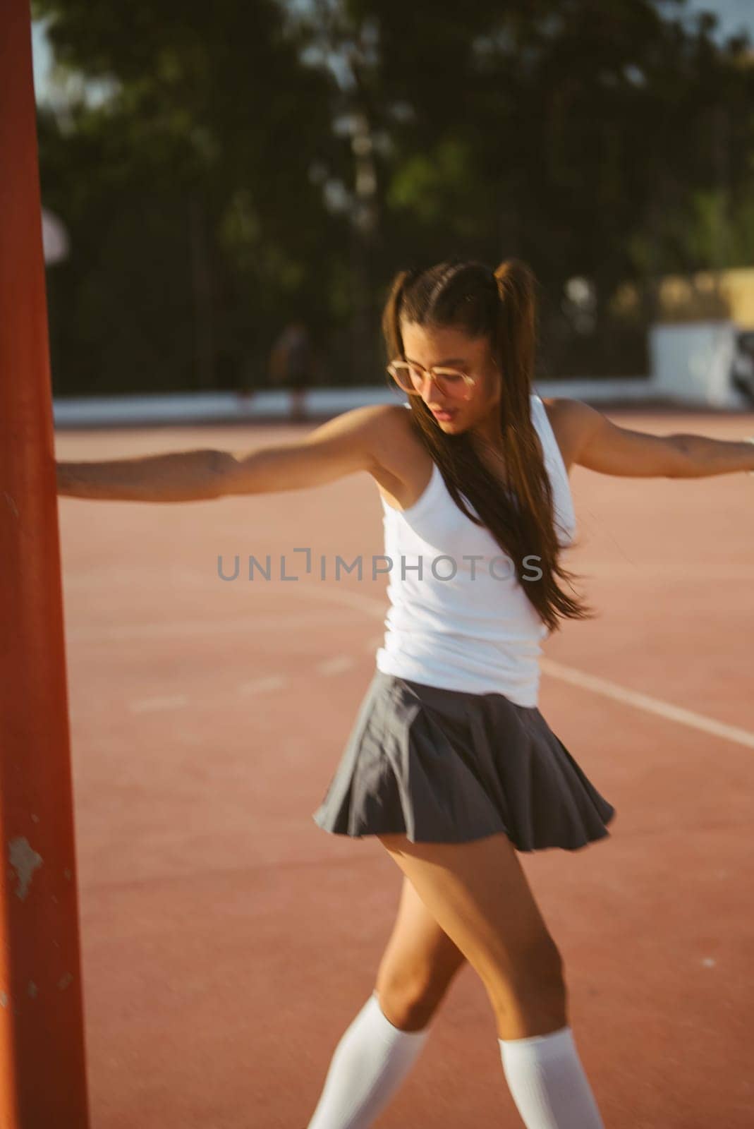 Energetic young girl dressed in sporty attire joyfully enjoying her outdoor playtime on the court area