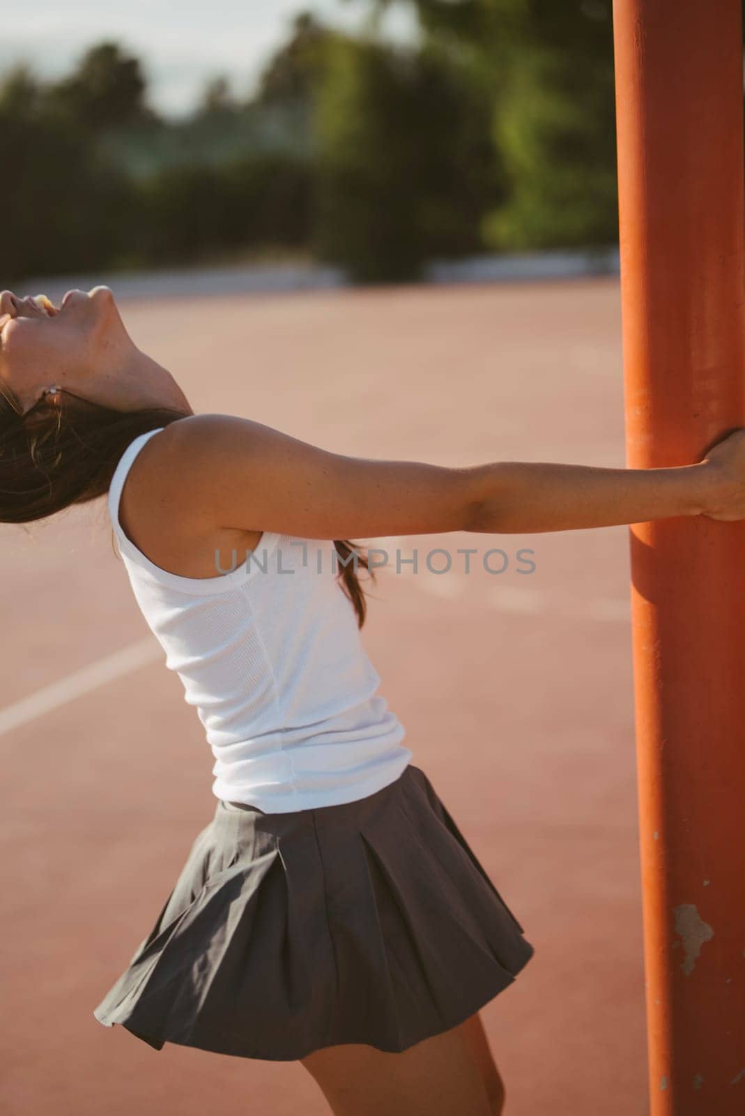 Sporty female in a stylish skirt strikes a dynamic pose outdoors, showcasing athleticism and energy.