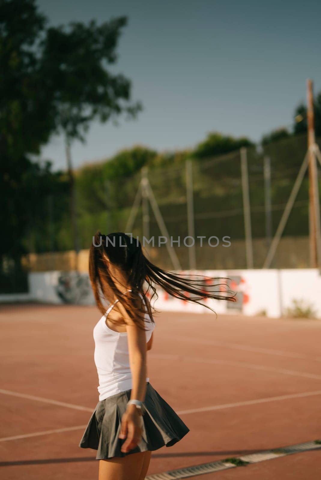 A girl joyfully spinning on a sunny court, embracing the essence of youthful spirit, freedom, and fun