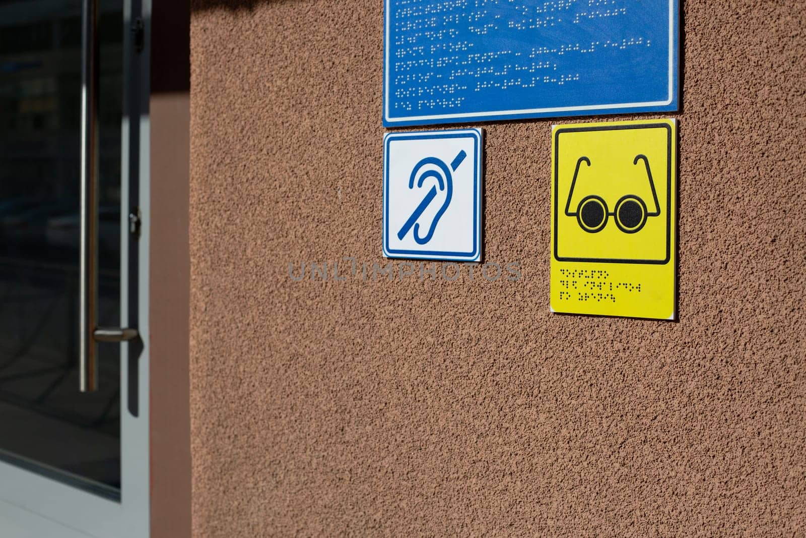 Social care conditions for people with disabilities, glasses and ear icon for blind and deaf people with information in braille text at entrance to building, accessible zone for disabled people