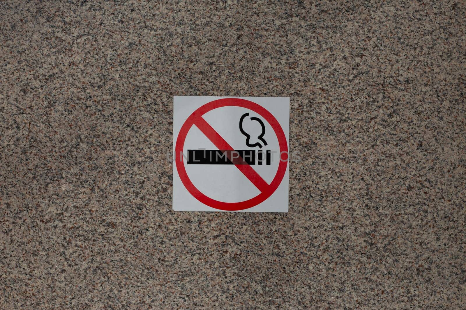 Sticker with crossed out cigarette on marble wall of building, ban on smoking in public place with special sign, social problem and smoking addiction