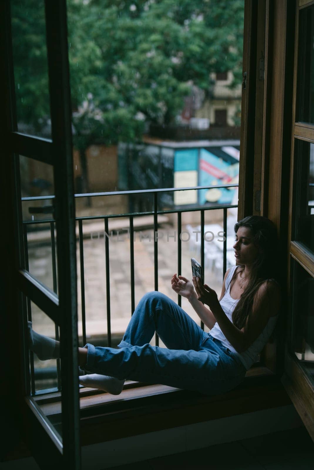 A serene scene of a person sitting by a window, enjoying a moment of leisure and connection with nature.