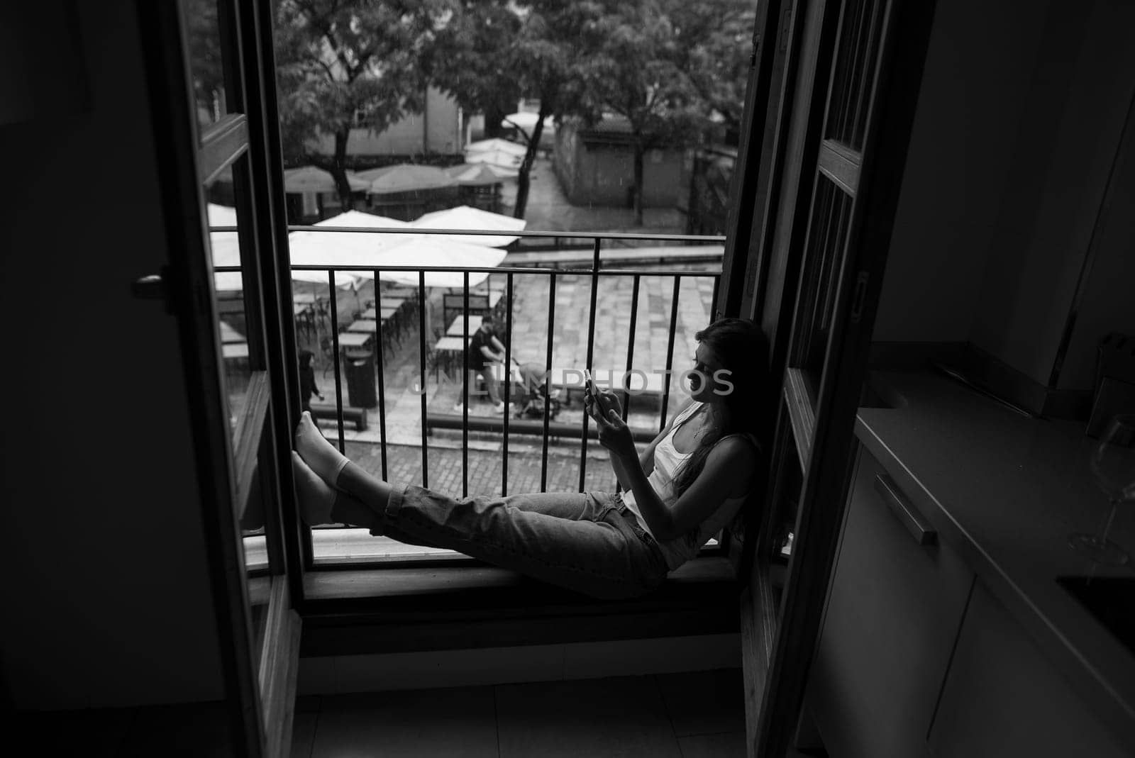 A person is sitting quietly by the window, deep in thought, completely lost in the surrounding calm of nature