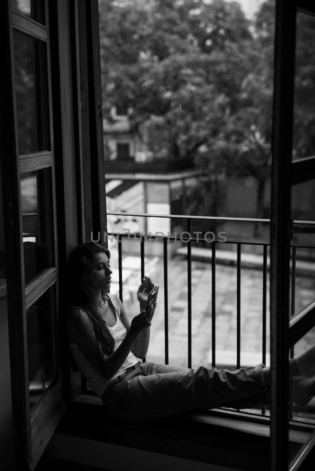 A person sits thoughtfully in a cozy window nook, quietly reflecting and evoking a deep sense of solitude
