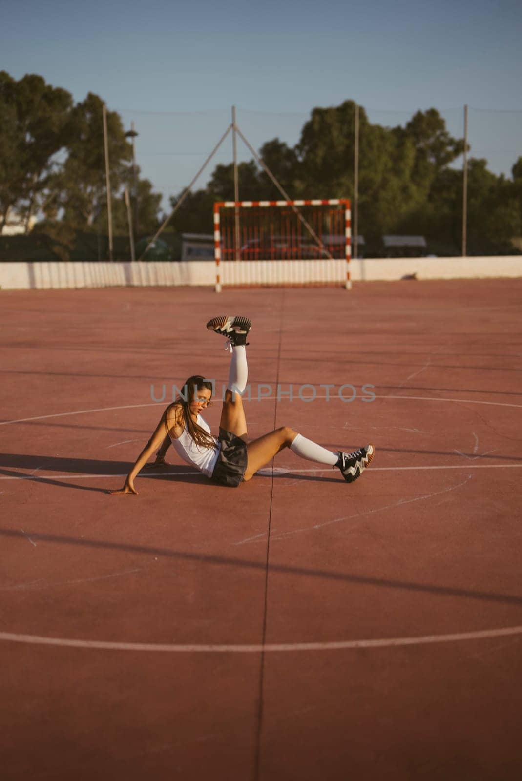 An impressive athlete showcases remarkable flexibility and athleticism while on a sunlit outdoor sports court area