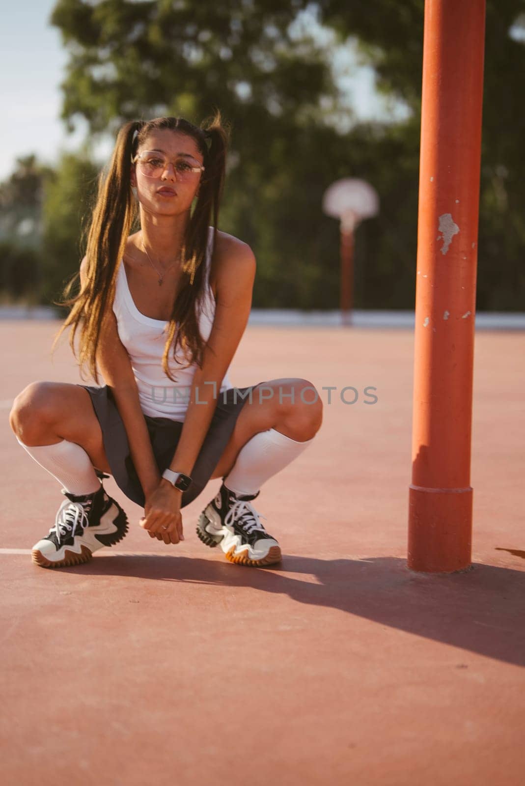 A young female athlete confidently poses on a vibrant basketball court, showcasing her stylish sporty demeanor