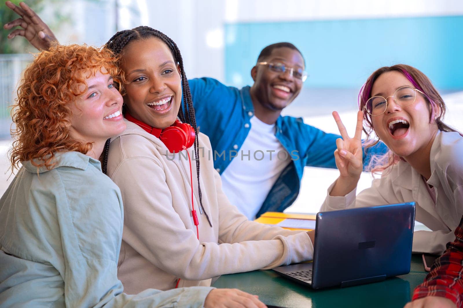 A group of four students with laptops and notes sit near the campus to review the exam.tudents with laptops sit near the campus and communicate looking at camera
