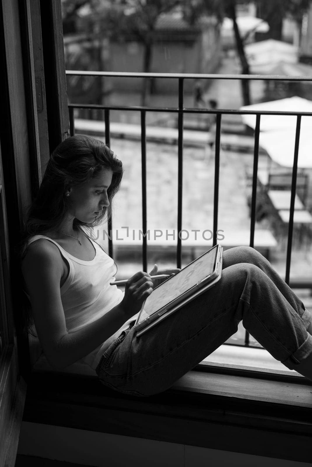 A dedicated artist calmly sketches away in a cozy nook by the window, surrounded by the beauty of nature