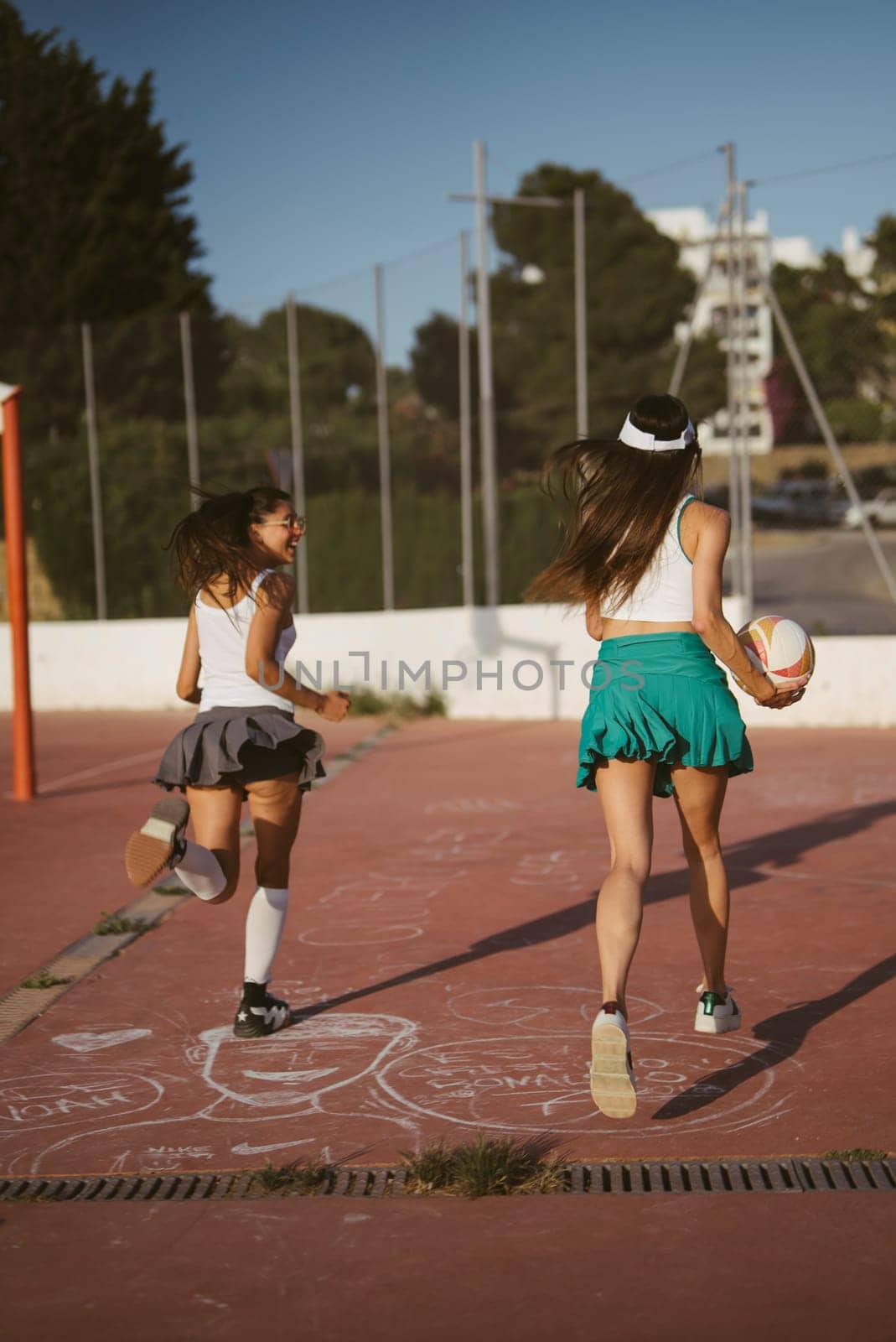 Two energetic girls are fully engaged in a playful and fun sports activity within a vibrant outdoor environment