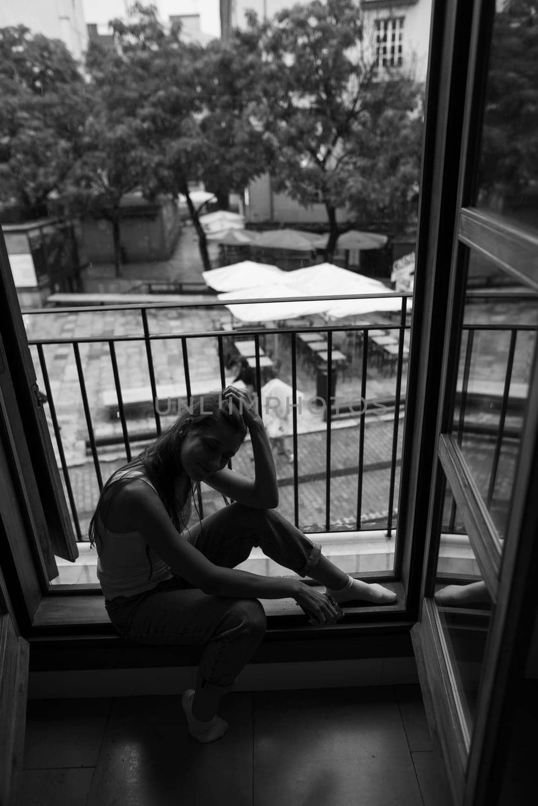 A reflective figure is seated by the window, capturing both solitude and deep introspection in beautiful monochrome