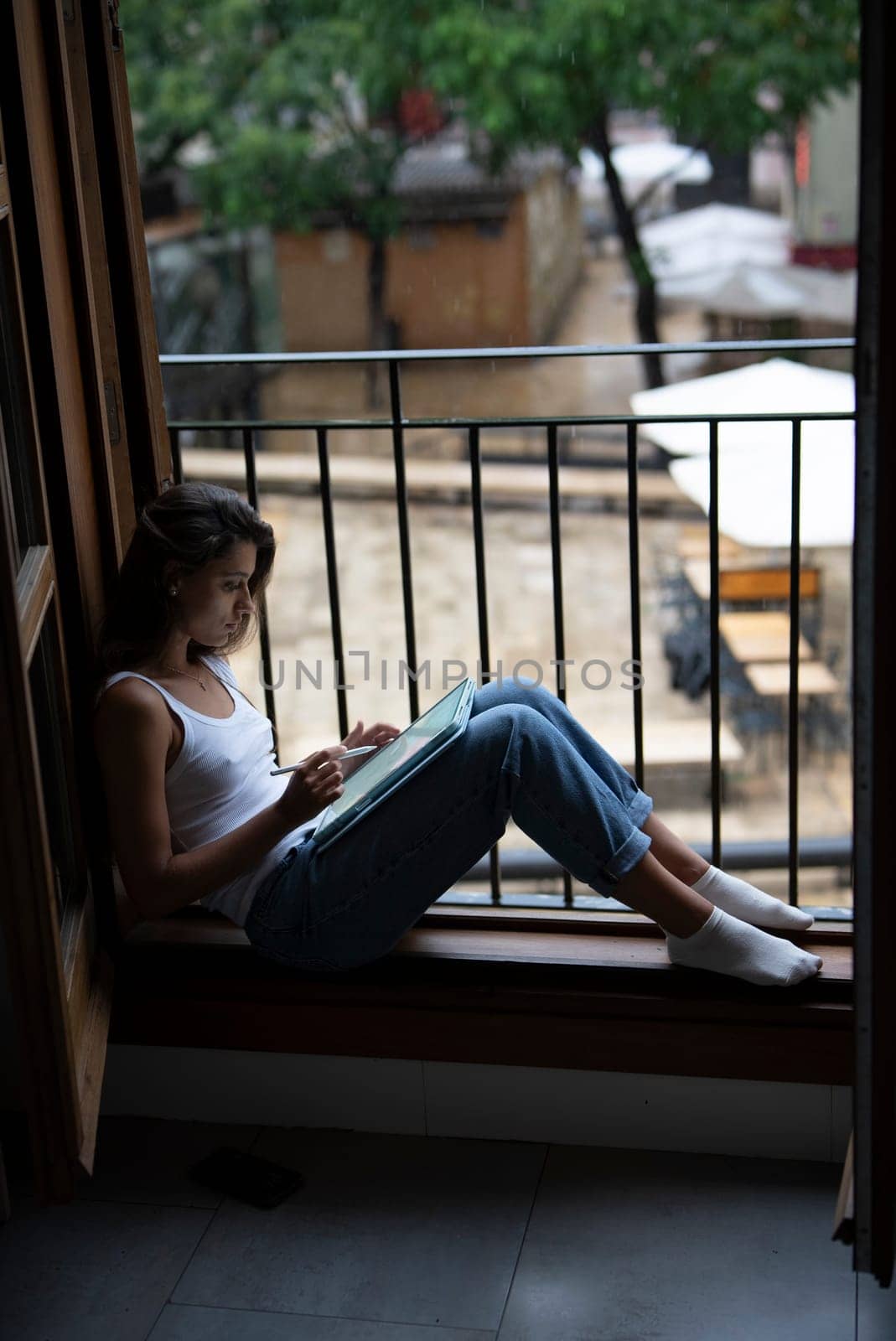 A young woman finds peace as she relaxes in a cozy window nook, deeply lost in thought and surrounded by nature