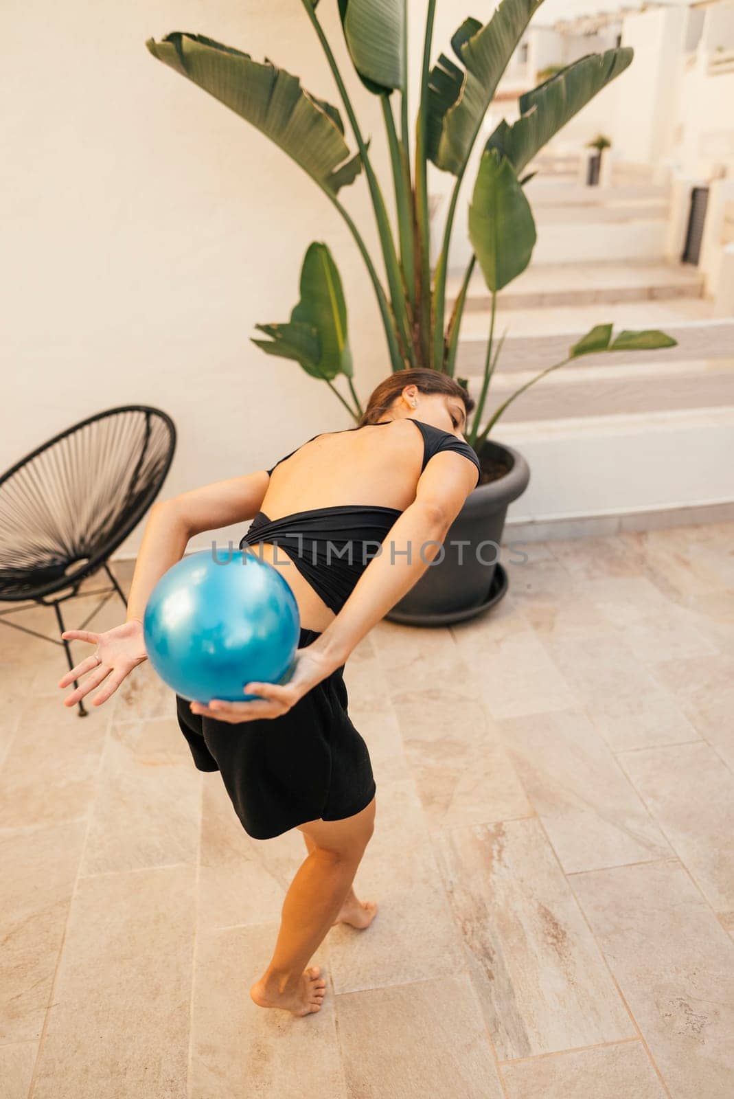 A woman impressively performs a unique yoga pose on a stability ball in a stylish, contemporary setting
