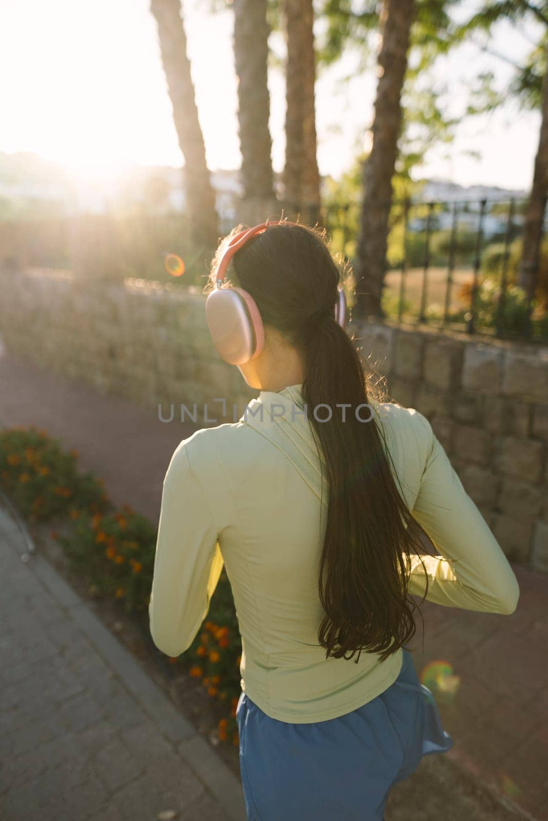 A woman is jogging outdoors, fully enjoying the warmth of the sunlight in a serene and beautiful natural setting