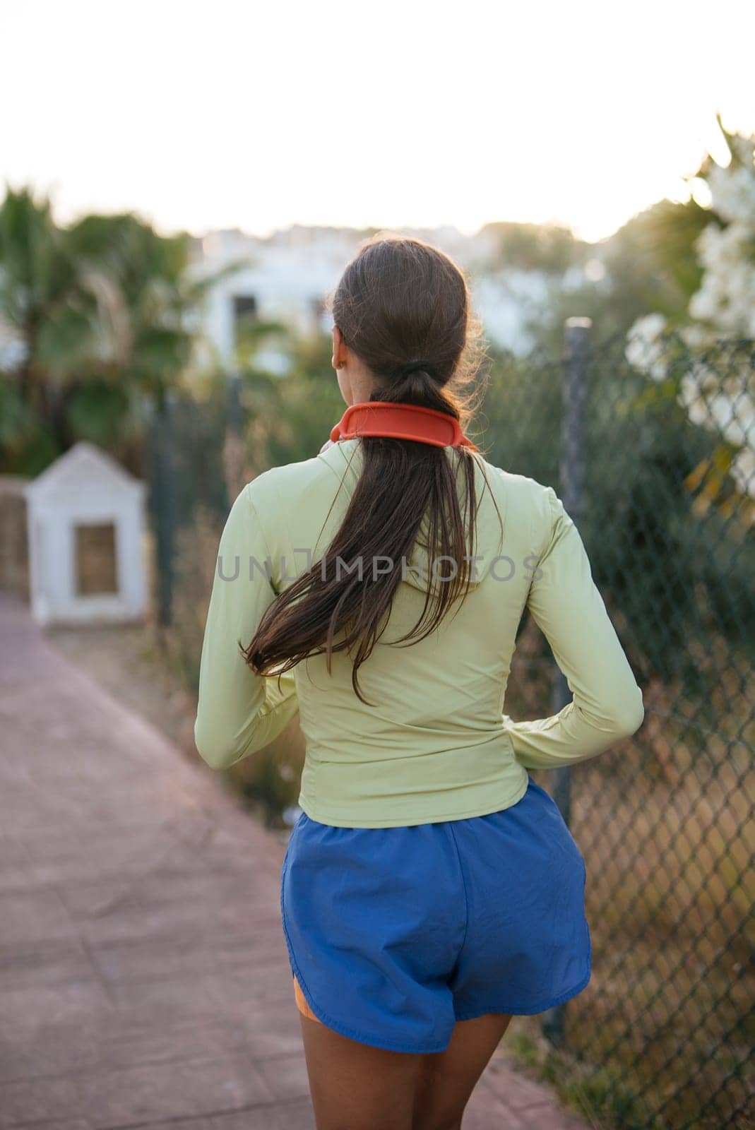 A woman leisurely strolls along a scenic path, donned in stylish activewear that enhances her vibrant energy