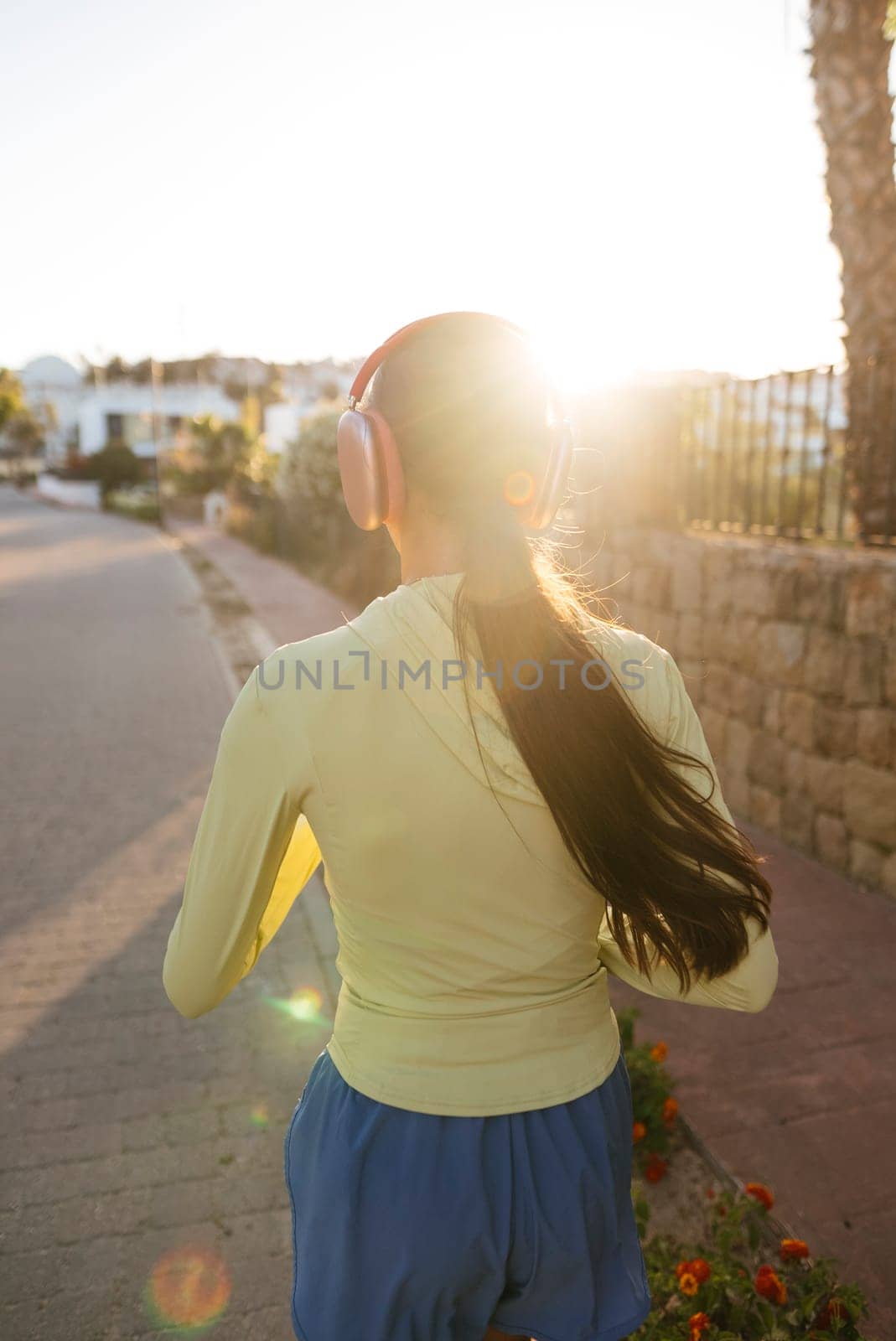 A young woman jogs outdoors at sunset, enjoying a healthy lifestyle and the freedom of exercising in nature