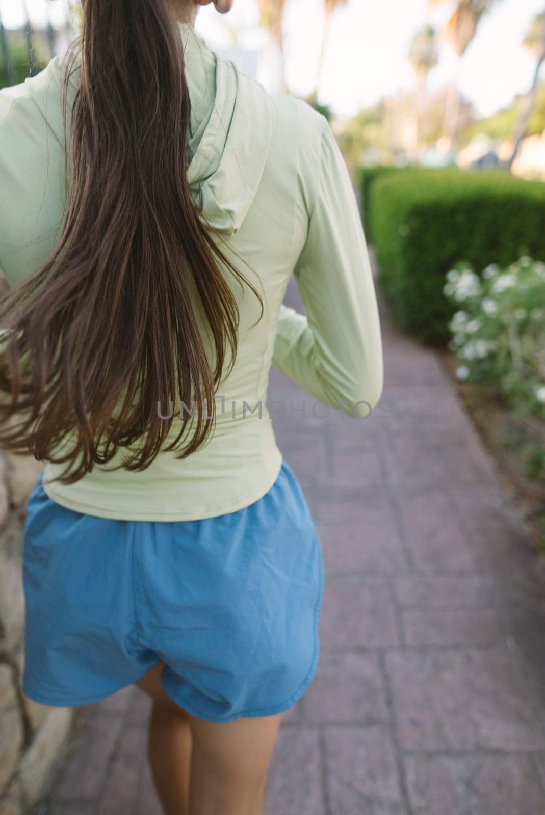 A young woman leisurely walks along a beautiful path in a sunny environment, promoting health and leisure activities