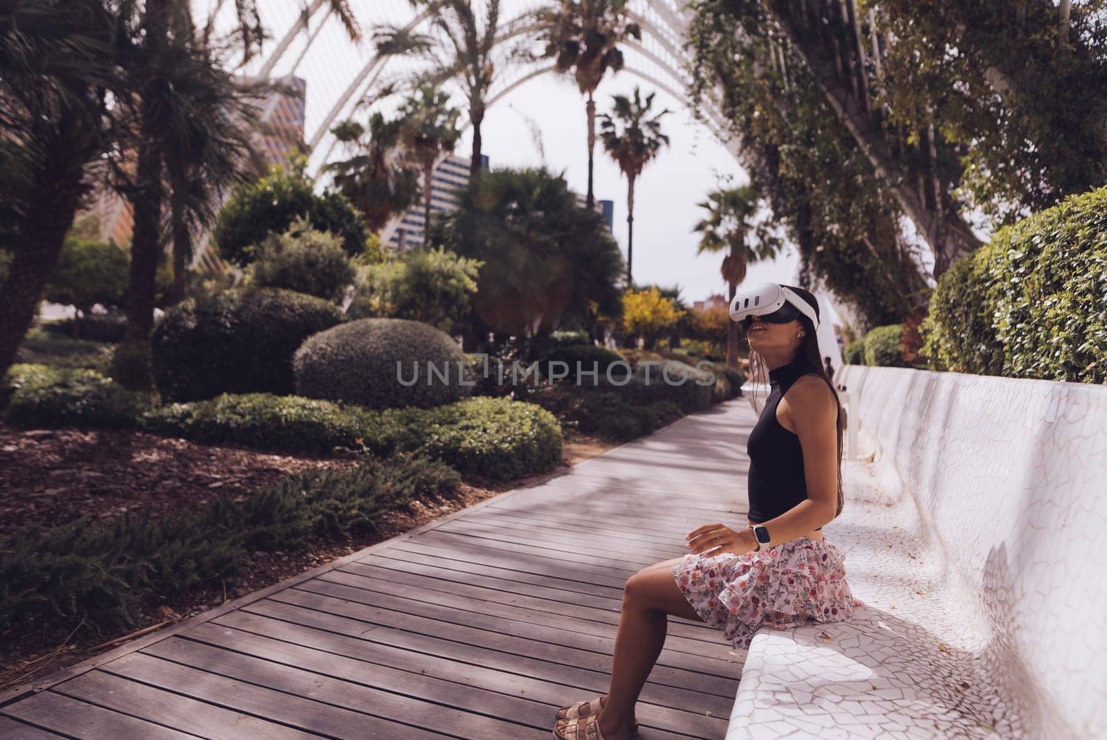 A woman is enjoying a calm and serene moment while sitting on a bench surrounded by lush tropical greenery