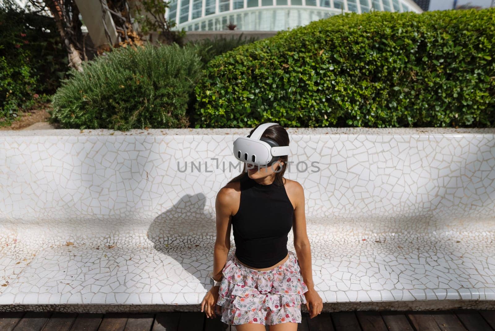 A young girl enjoys a captivating VR experience outdoors while wearing a headset in the sunny setting