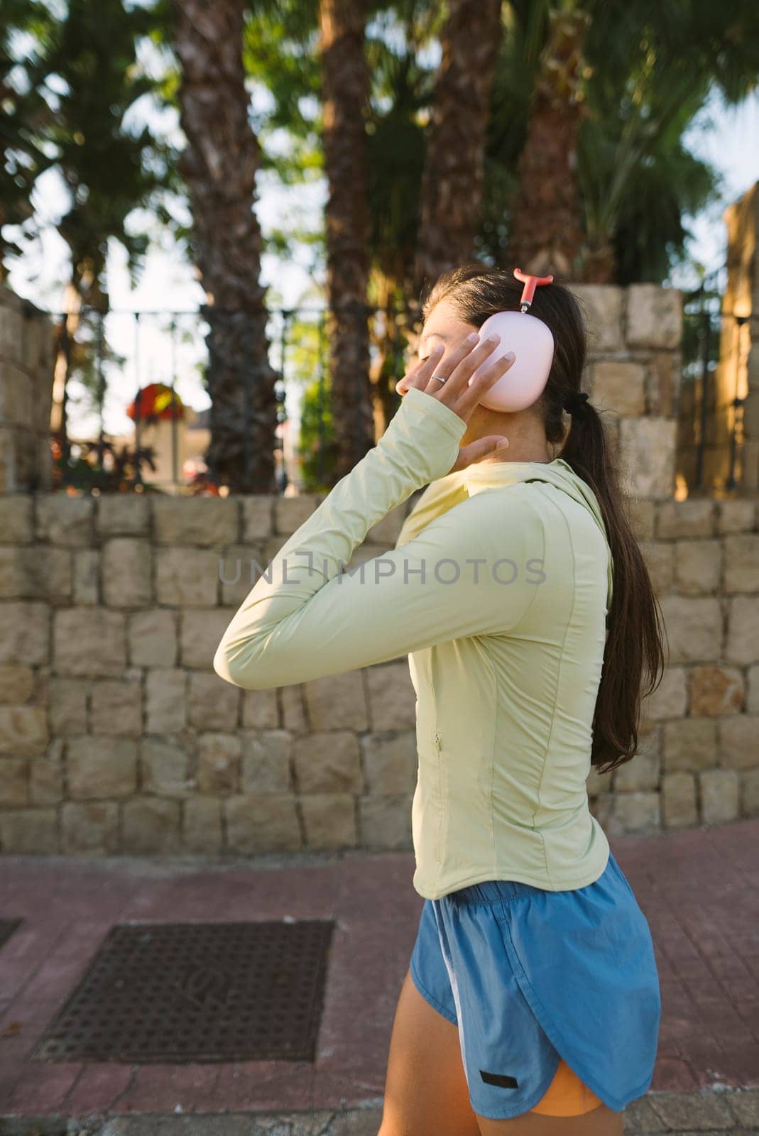 A young woman enjoys a peaceful outdoor walk, listening to her favorite music through headphones, amidst nature