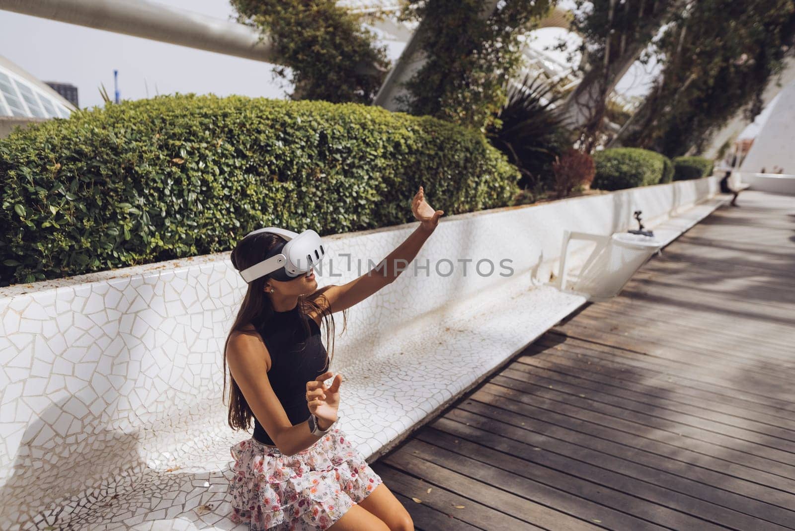 A vibrant young woman enjoys a leisurely moment outdoors, partaking in modern activities under the sunshine