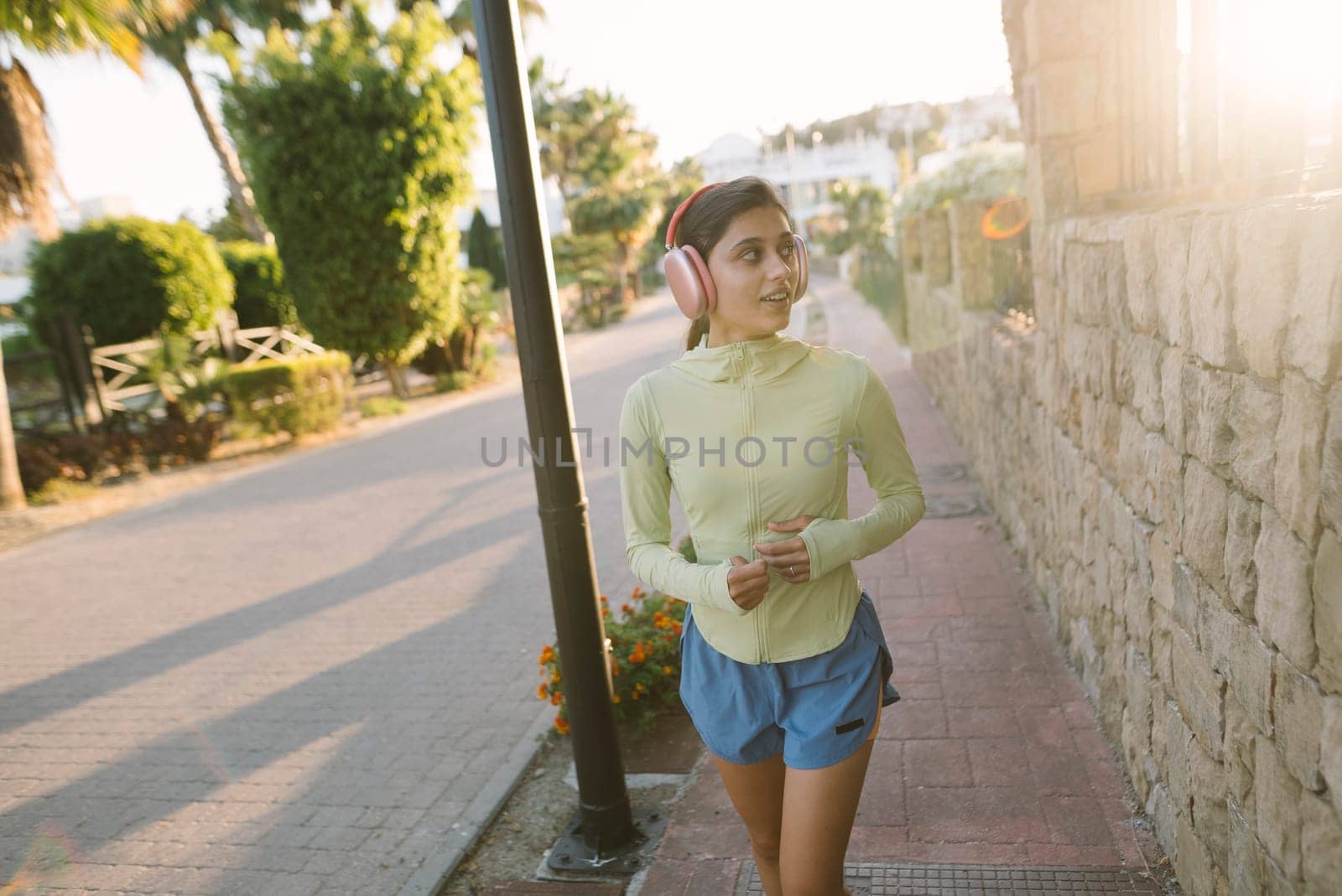 A young woman delights in a leisurely stroll through an urban area, relishing the warm glow of a sunset