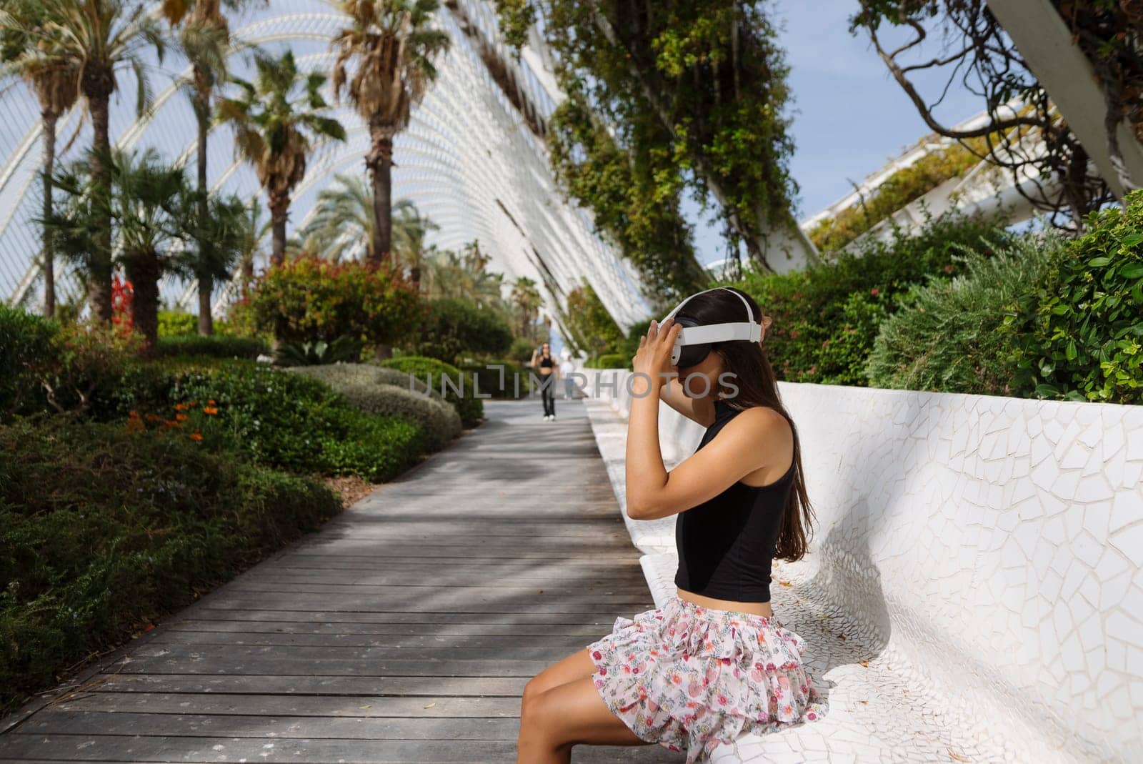 A woman immersed in virtual reality, surrounded by nature and palm trees, creating a serene atmosphere.