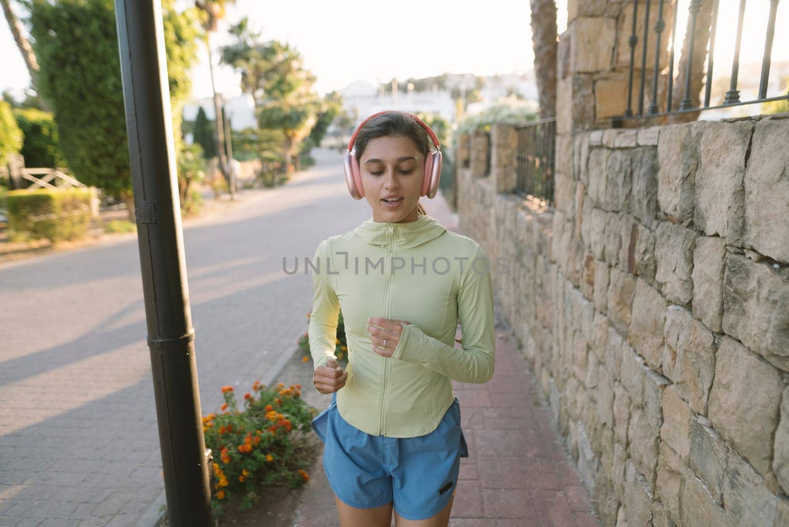 A young woman is thoroughly enjoying her morning jog with headphones on, surrounded by beautiful nature all around her
