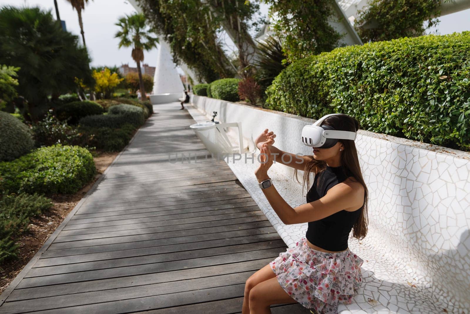 A young woman actively and vividly engages with immersive virtual reality while exploring a vibrant outdoor environment