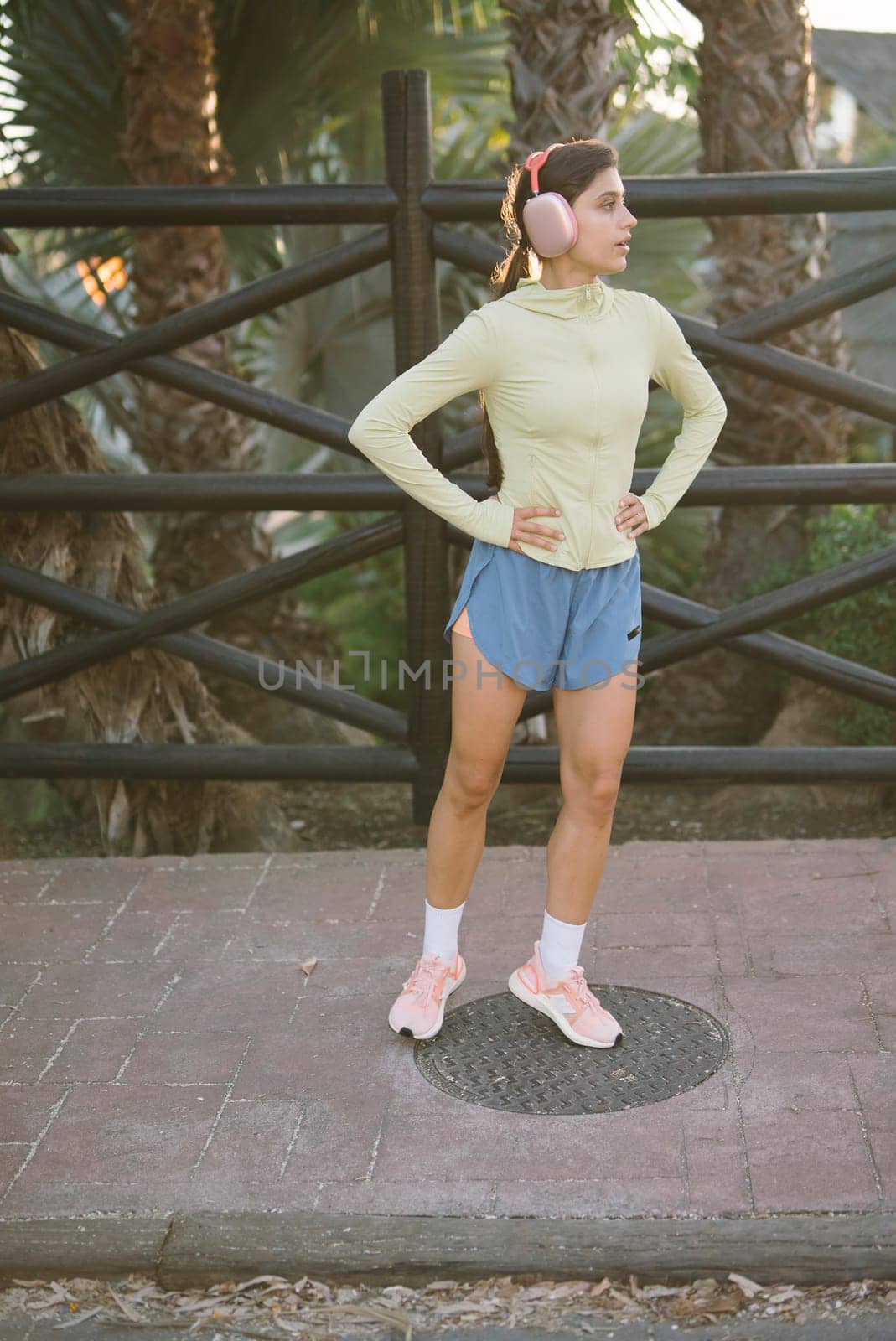 A young woman poses confidently in a fashionable athletic outfit against a beautiful outdoor backdrop