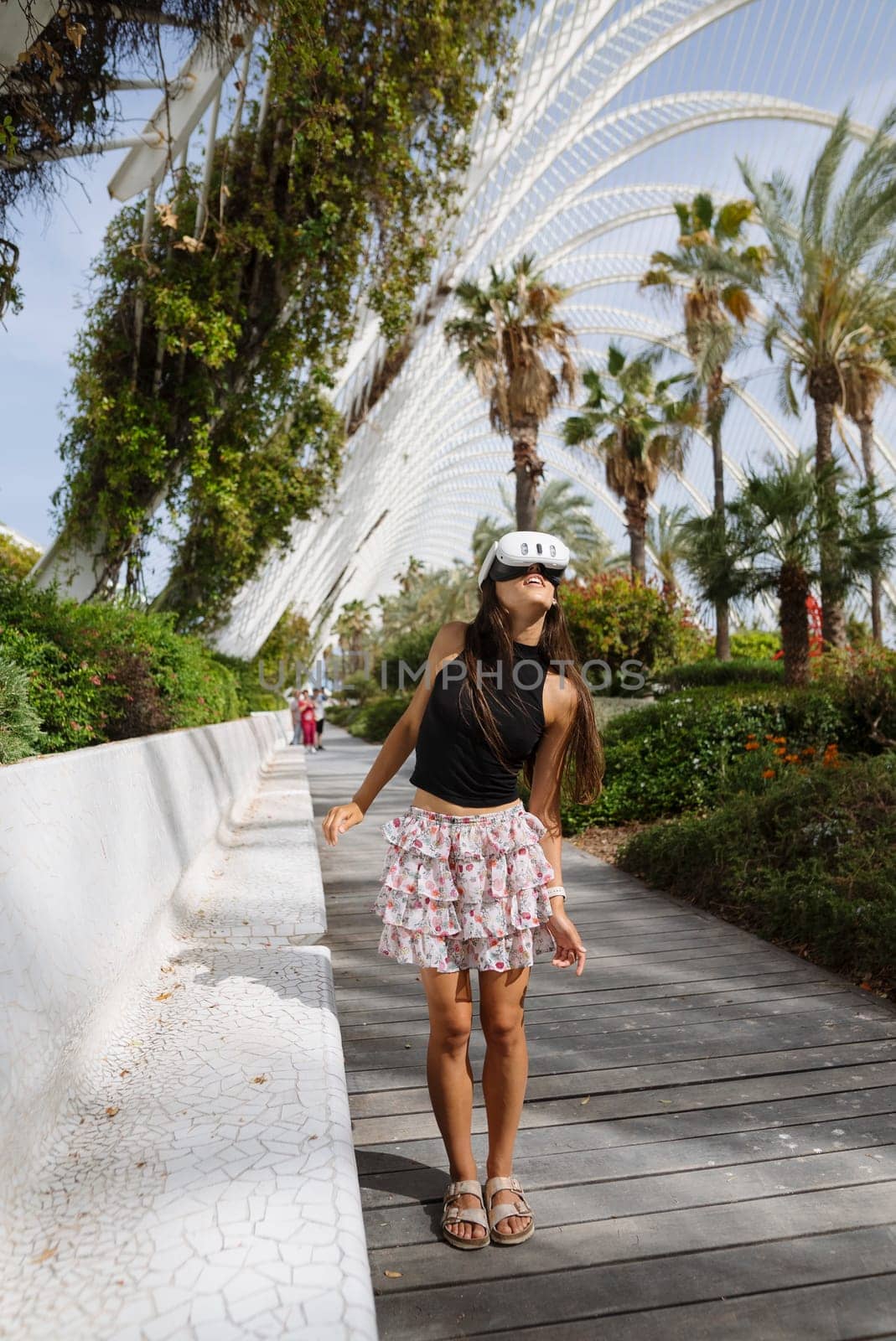 A trendy young woman poses in a skirt and helmet at a sunny park, embodying urban lifestyle and leisure.