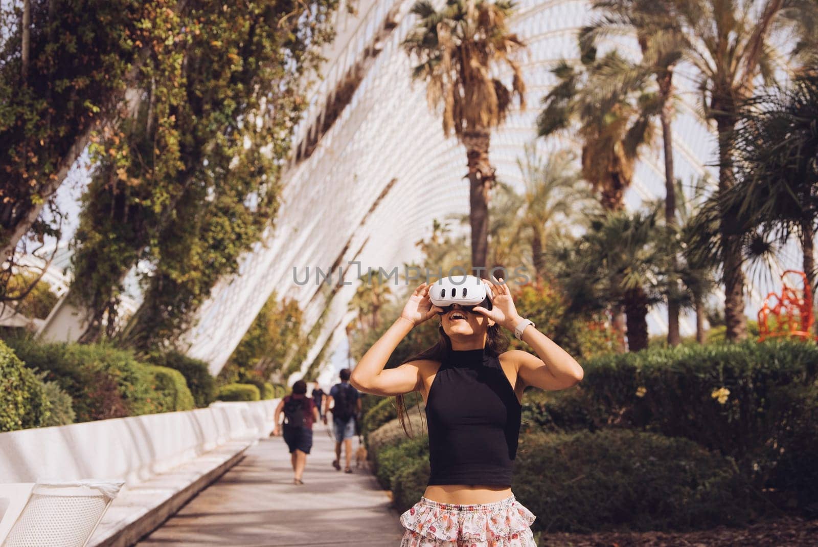 A fashionable woman enjoying her vibrant urban surroundings with cheerful palm trees and sleek buildings
