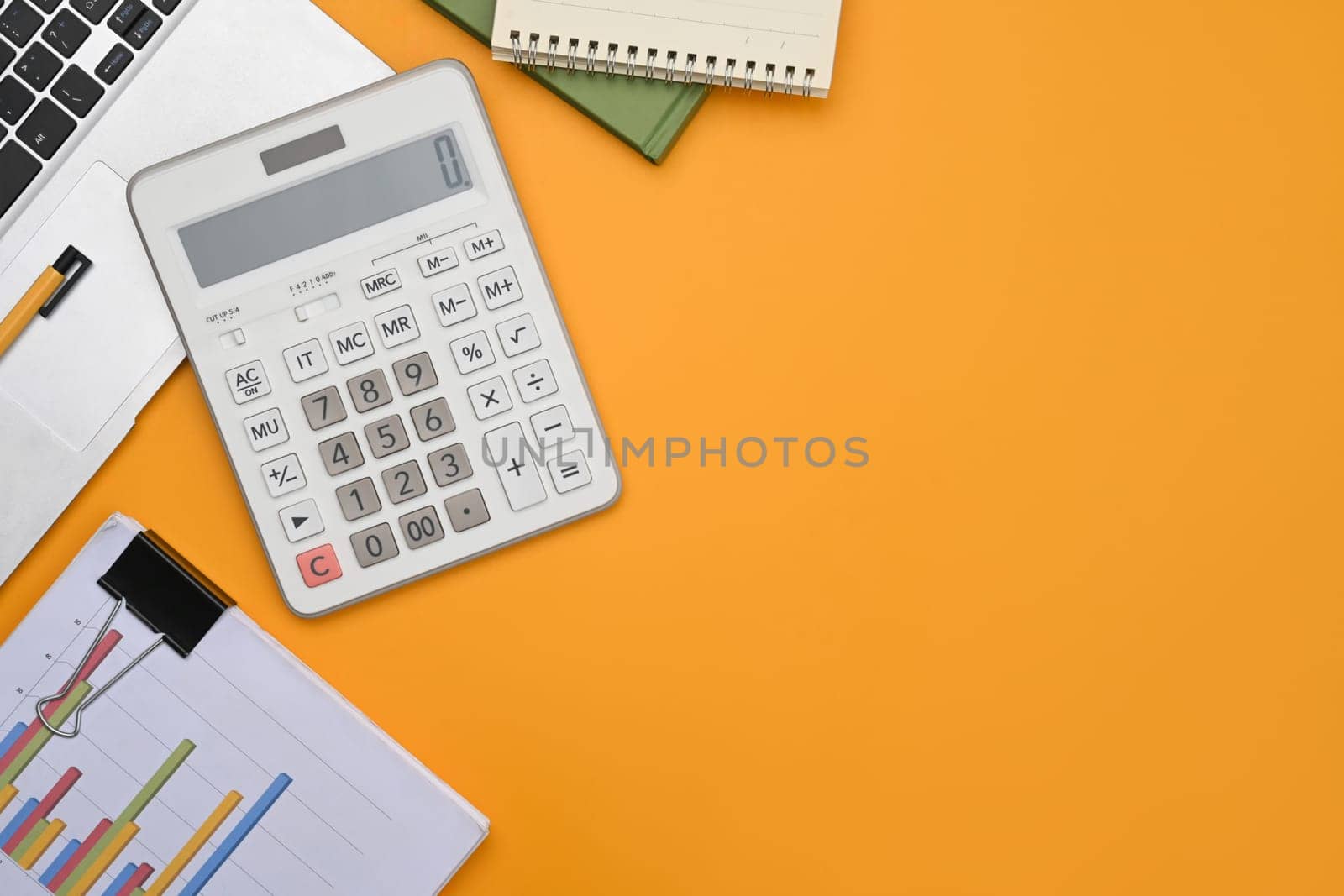 A calculator, laptop, financial reports and notepad on yellow background with space.