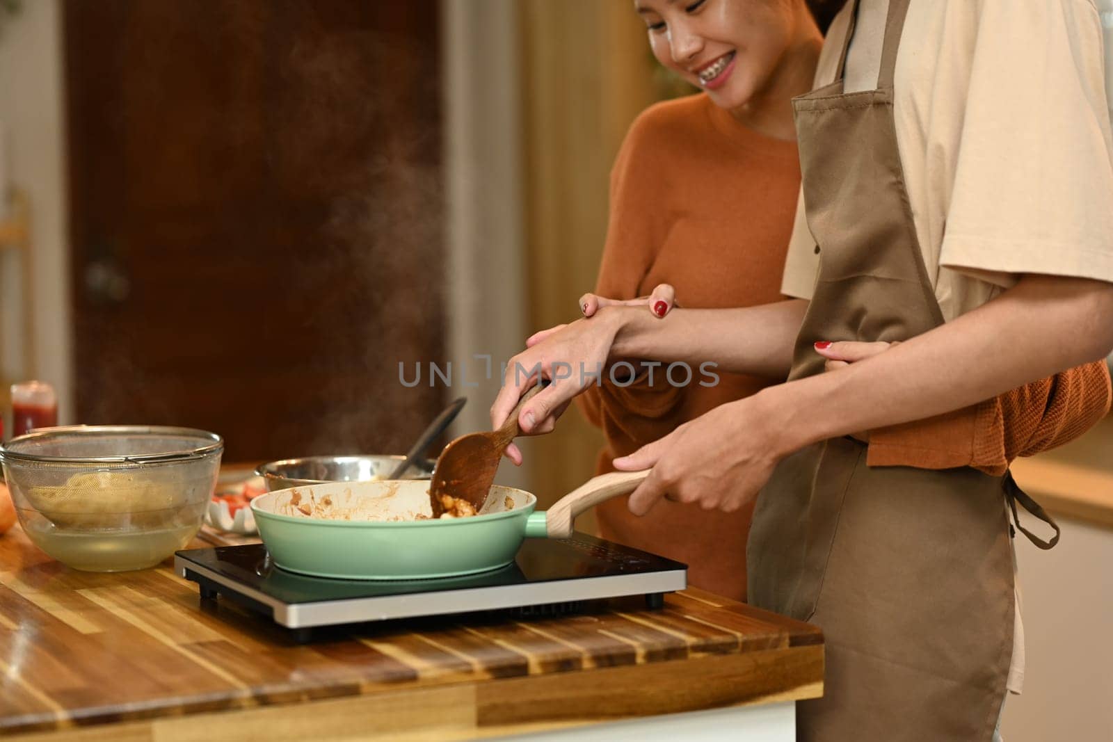 Happy young couple cooking pasta together in the kitchen. Relationships and happy domestic life.